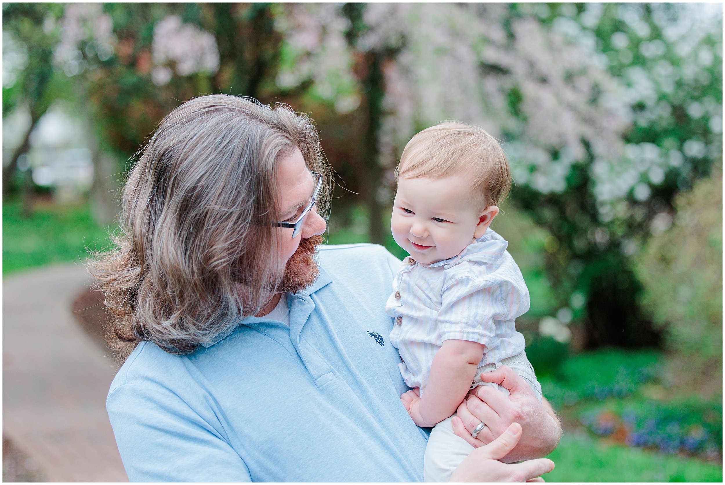 Dad holding baby during a spring family photo session with blooming trees in Silver Spring, Maryland