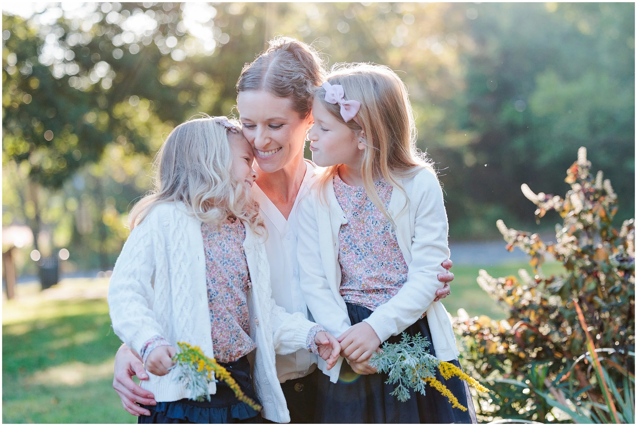 mom and two young daughters hugging and smiling during morning mini session