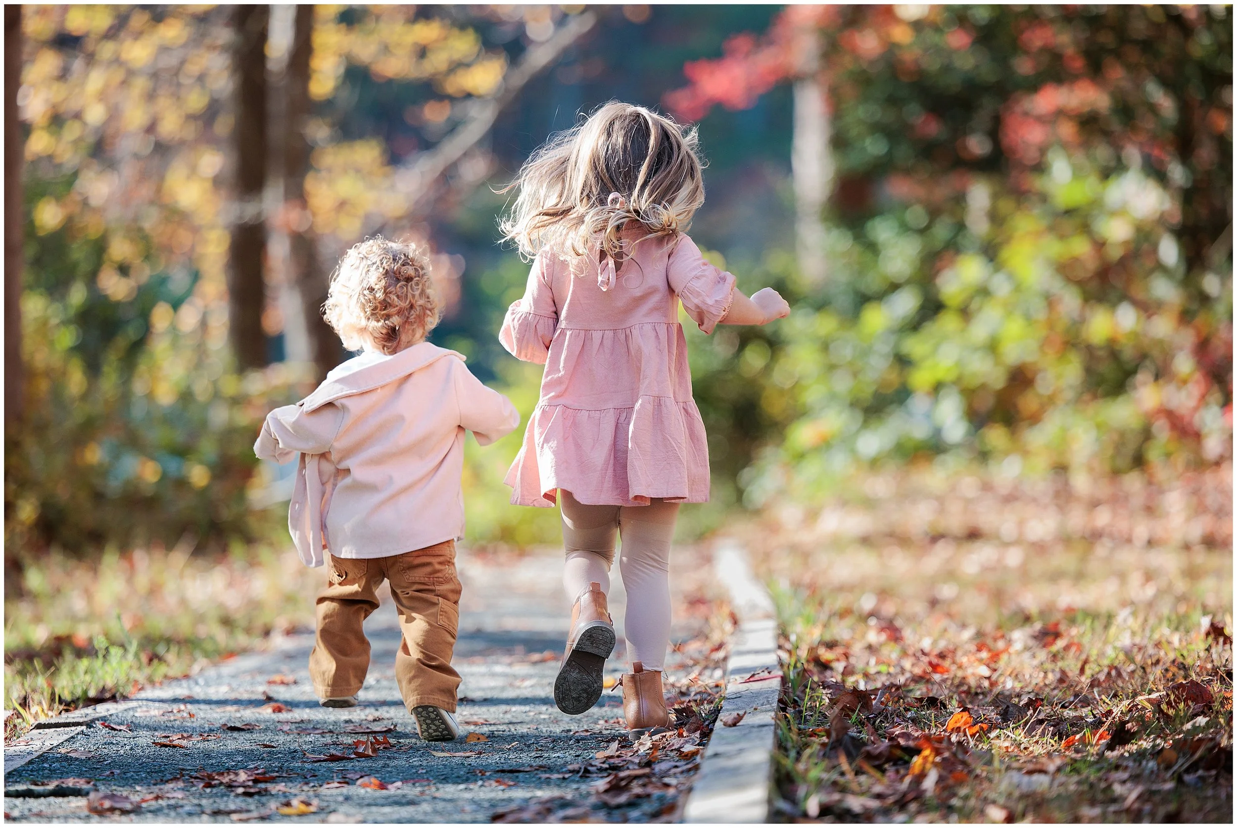 two kids running down a path during fall photo session in Maryland