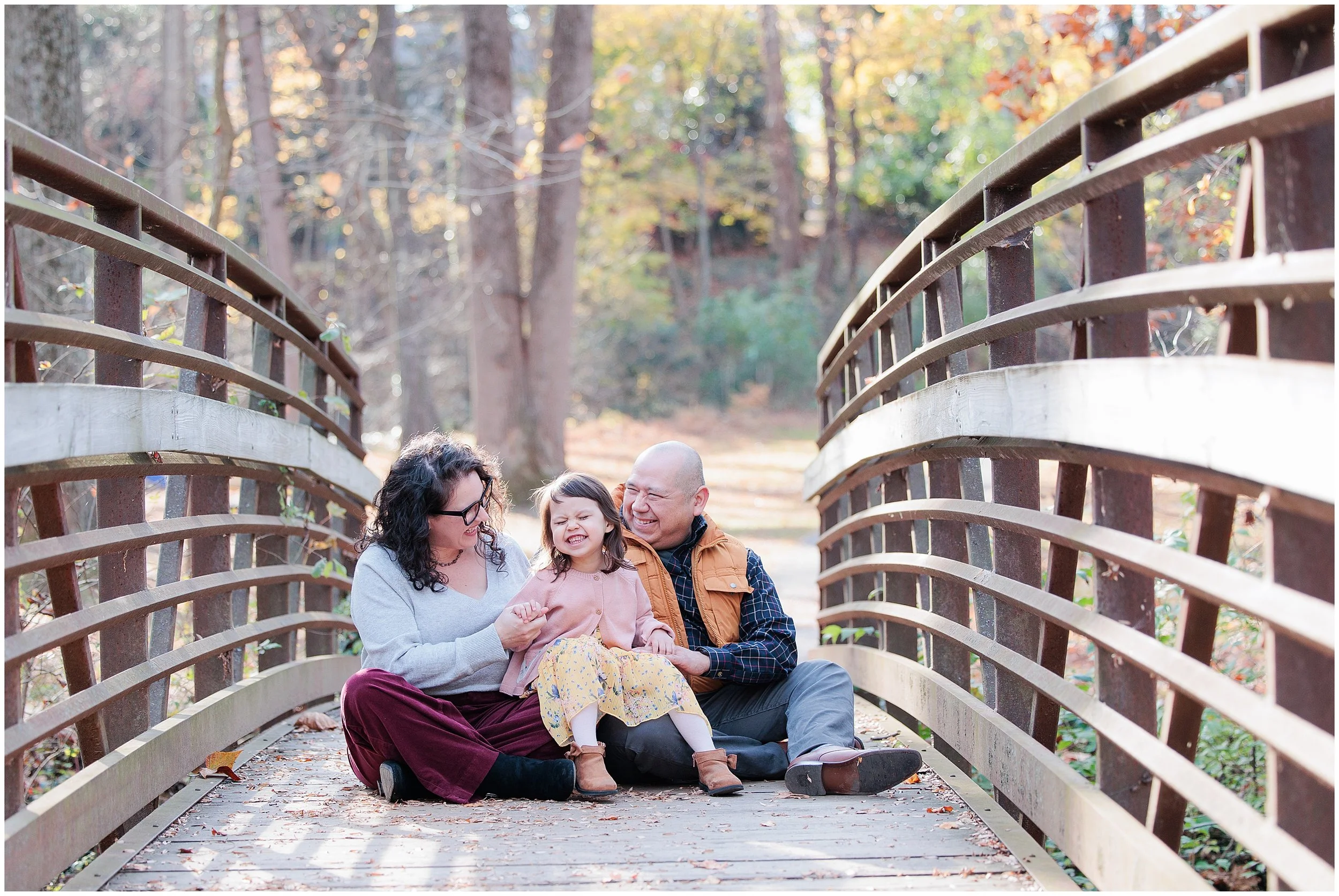 family sitting on bridge at Sligo Creek during fall family photo session