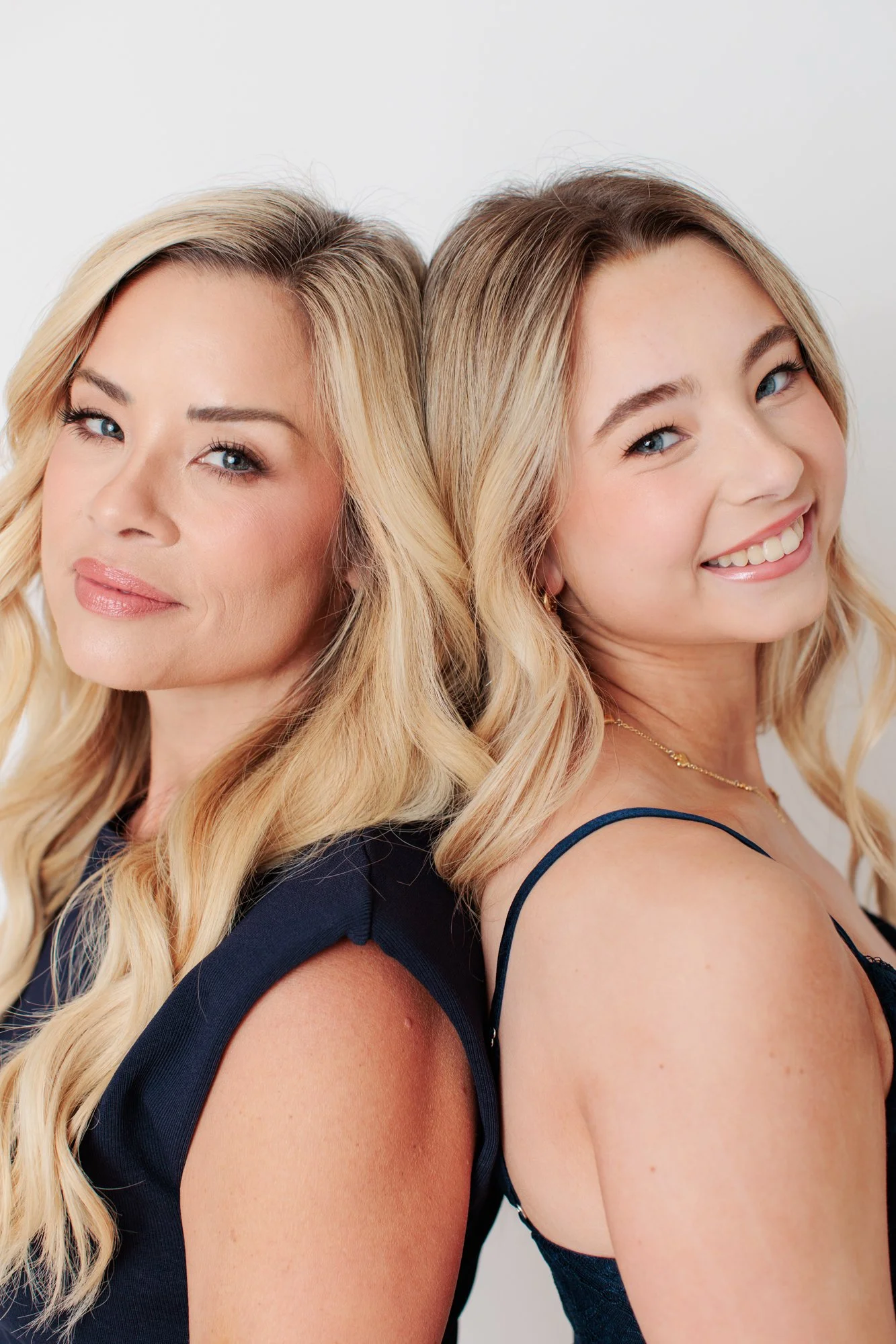 mother and daughter back to back looking at camera