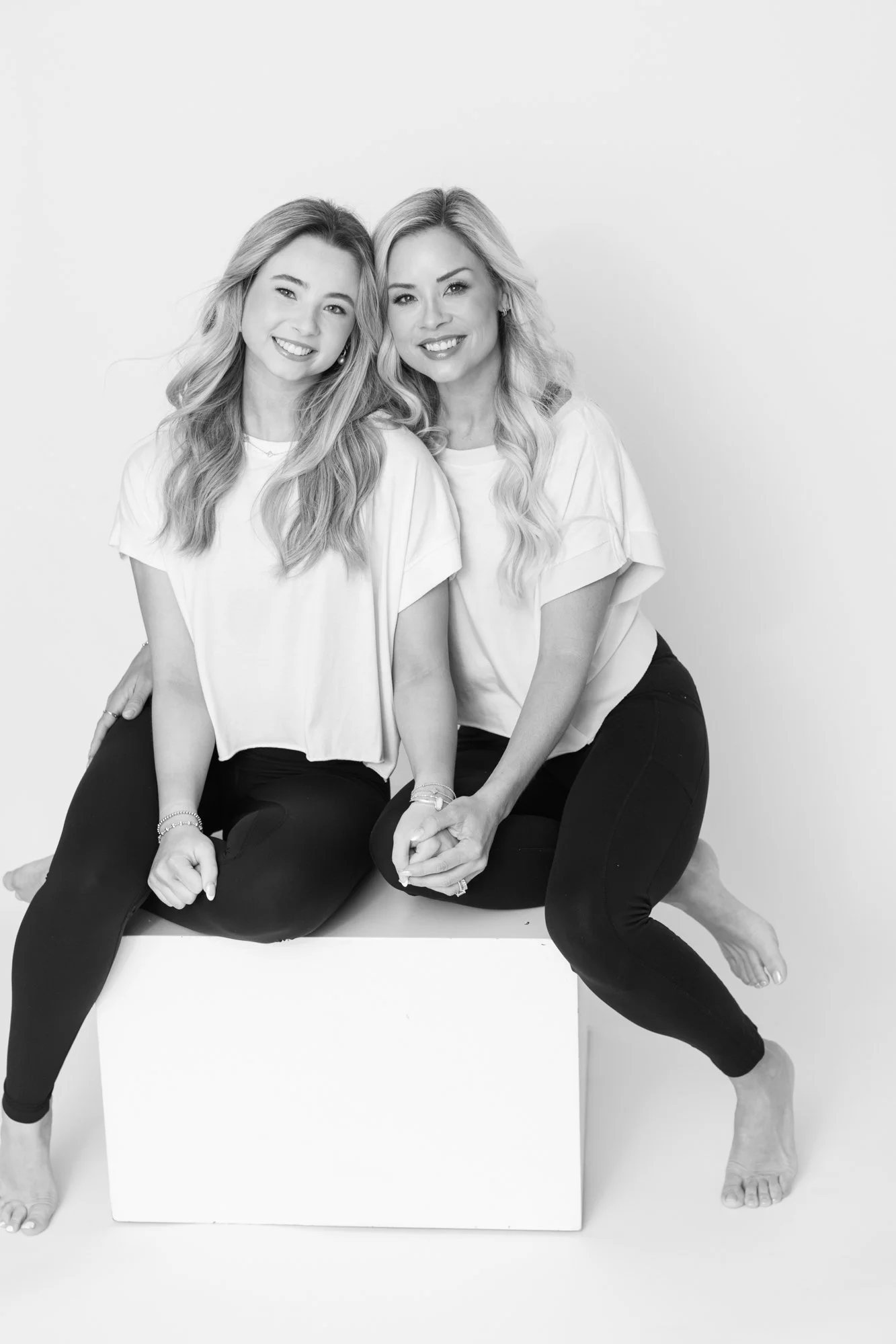  black and white image of mother and daughter sitting on white block together in Silver Spring Maryland studio 