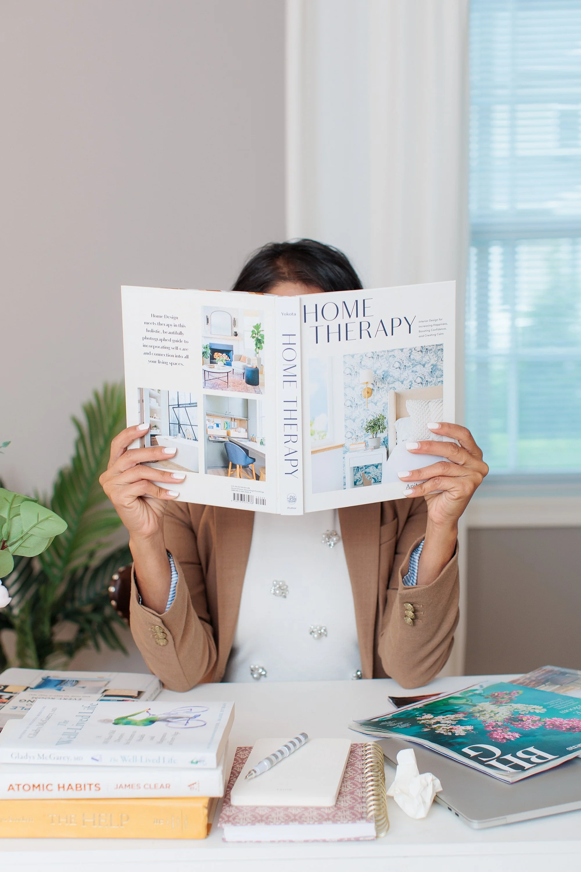 woman with face behind a book at a desk for branding session in Maryland