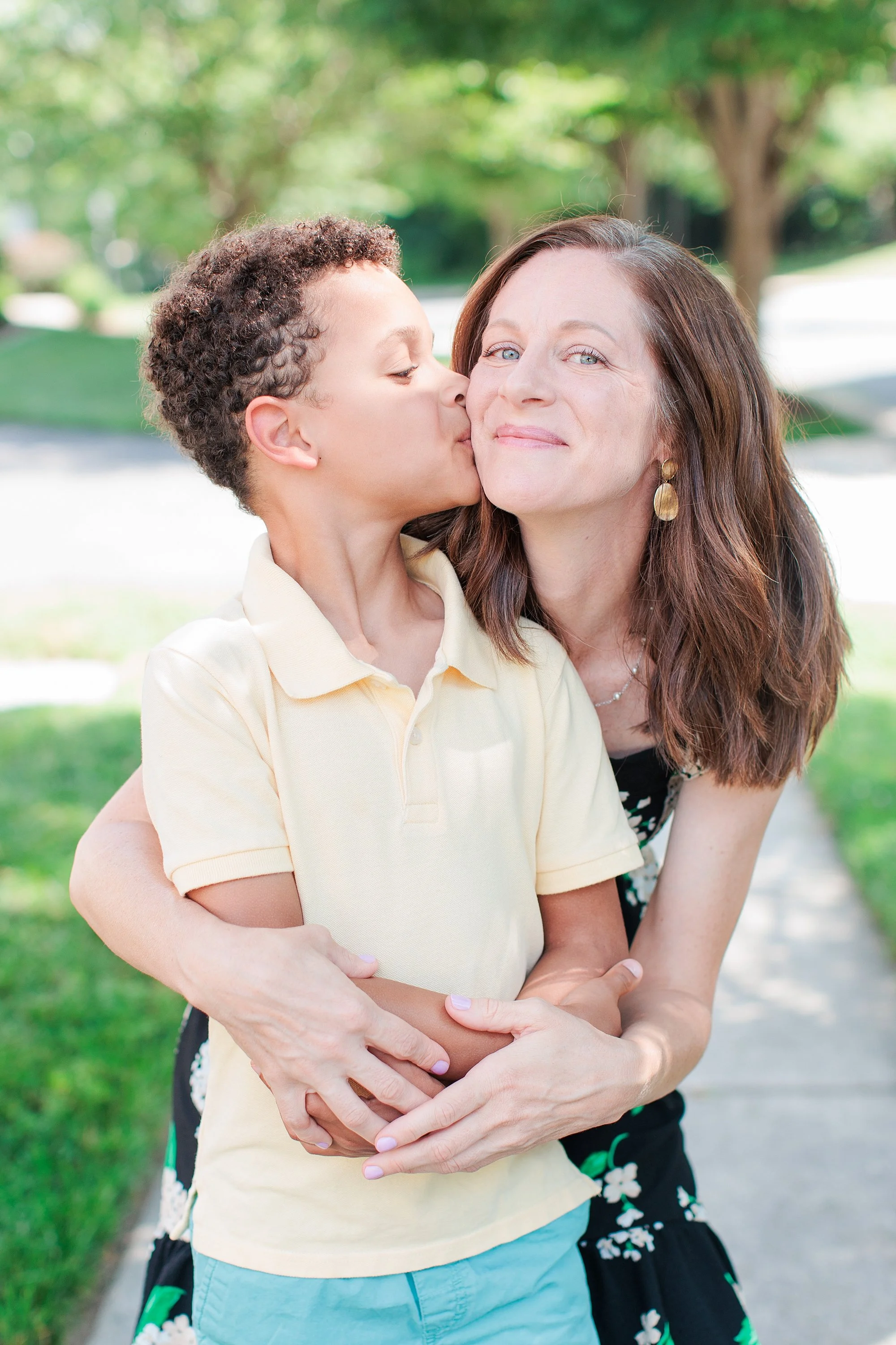 boy kissing mom's cheek during outdoor family photo session in Silver Spring MD