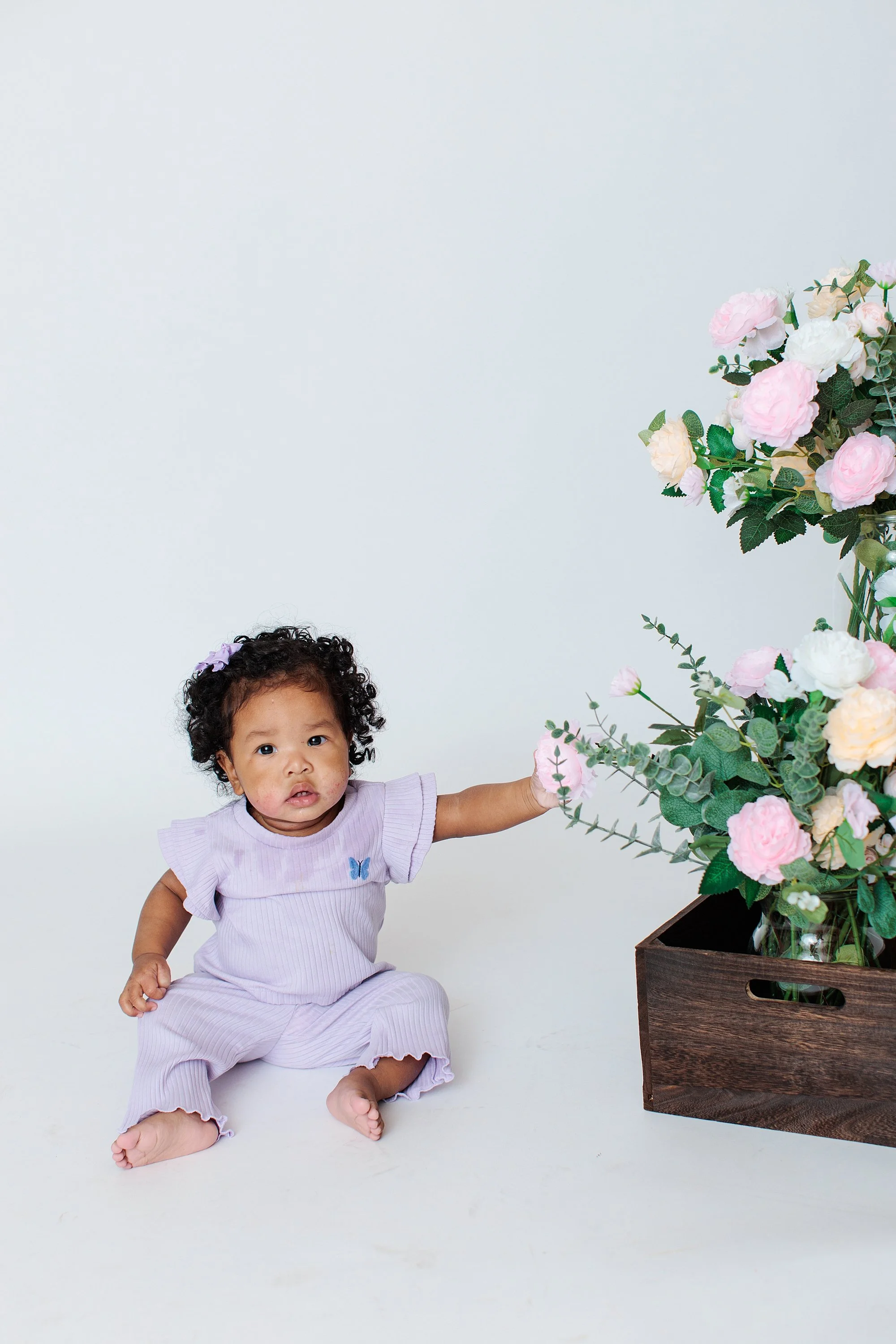 baby sitting on white floor during studio photo session in Maryland