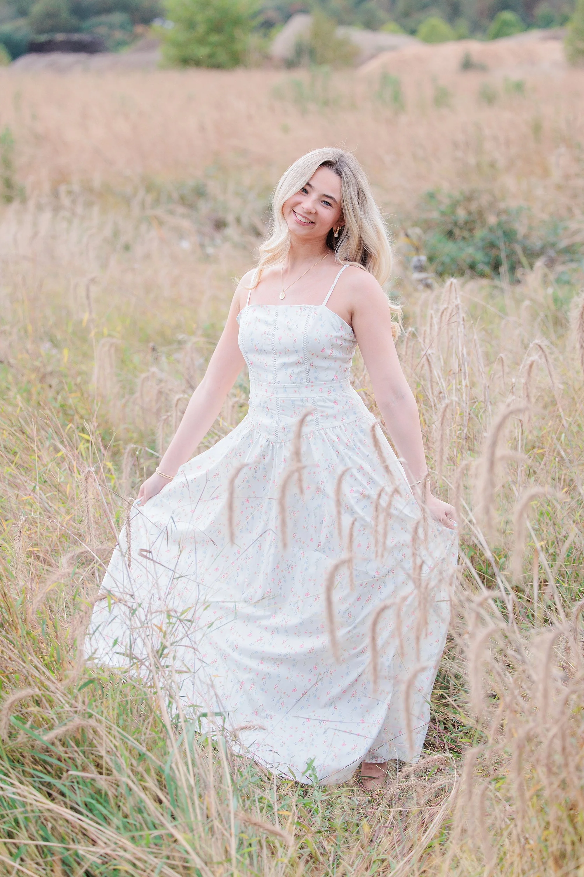 girl twirling dress in field during senior photo session