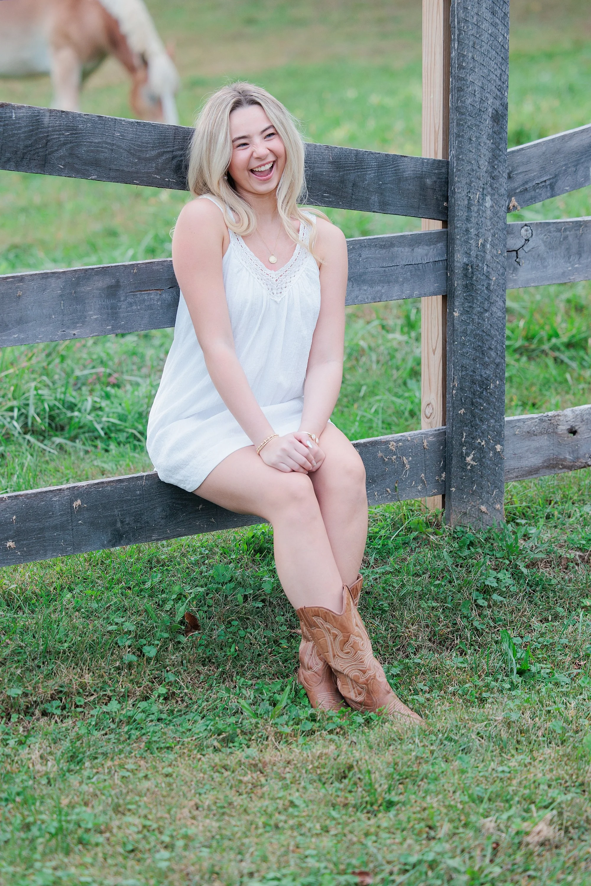sitting on fence during photo session for senior girl in Maryland