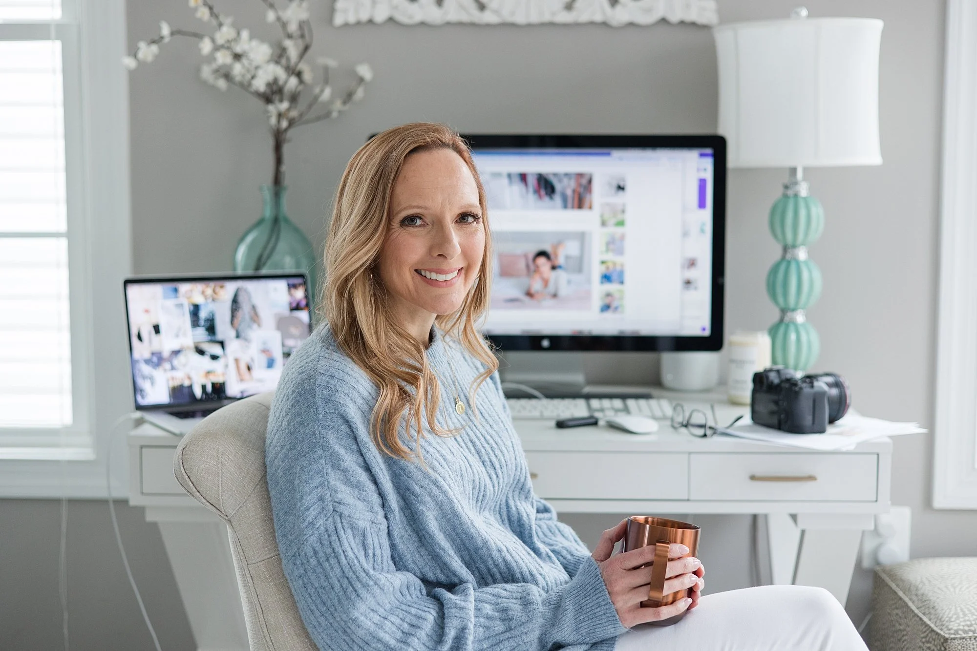 photographer in blue sweater sitting at desk with tea in Silver Spring MD