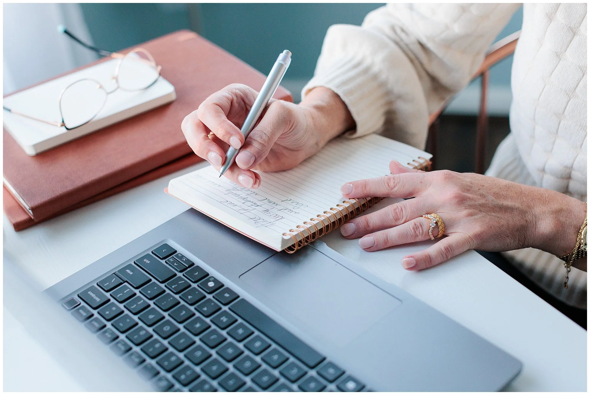 female entrepreneur sitting at laptop writing in a her notebook