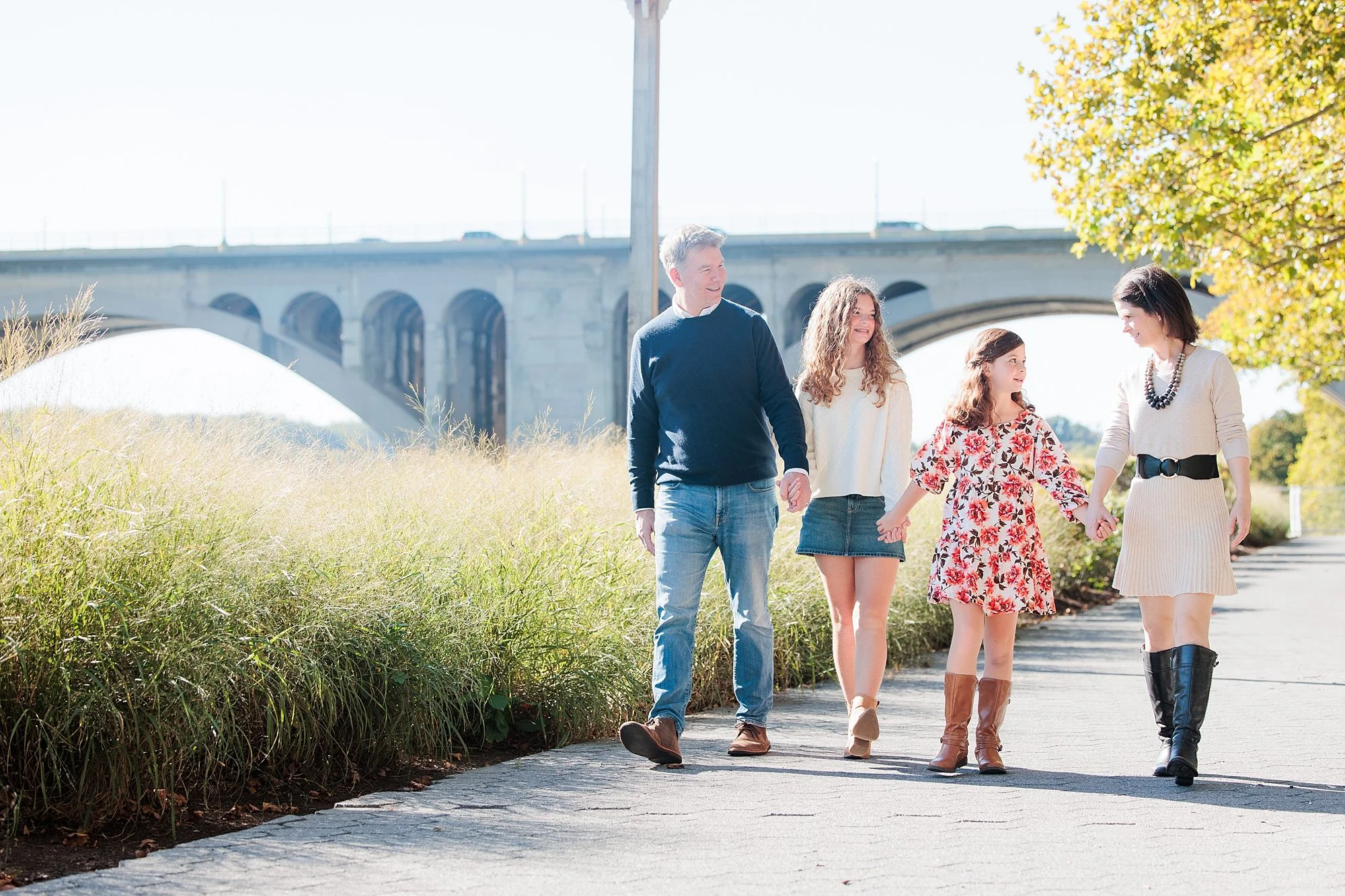 family walking Georgetown waterfront with key bridge in background