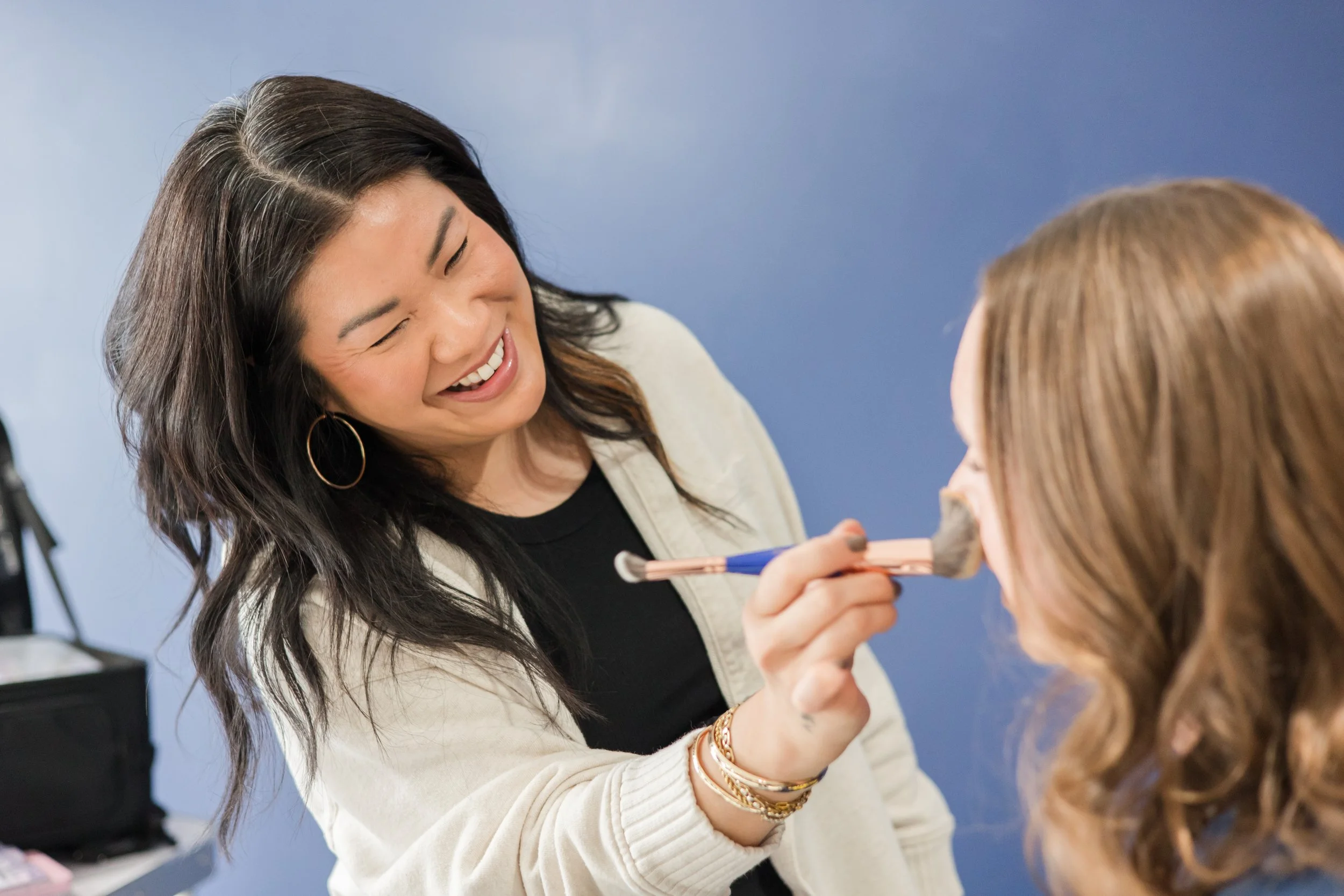 makeup artist doing women's makeup before studio photo session