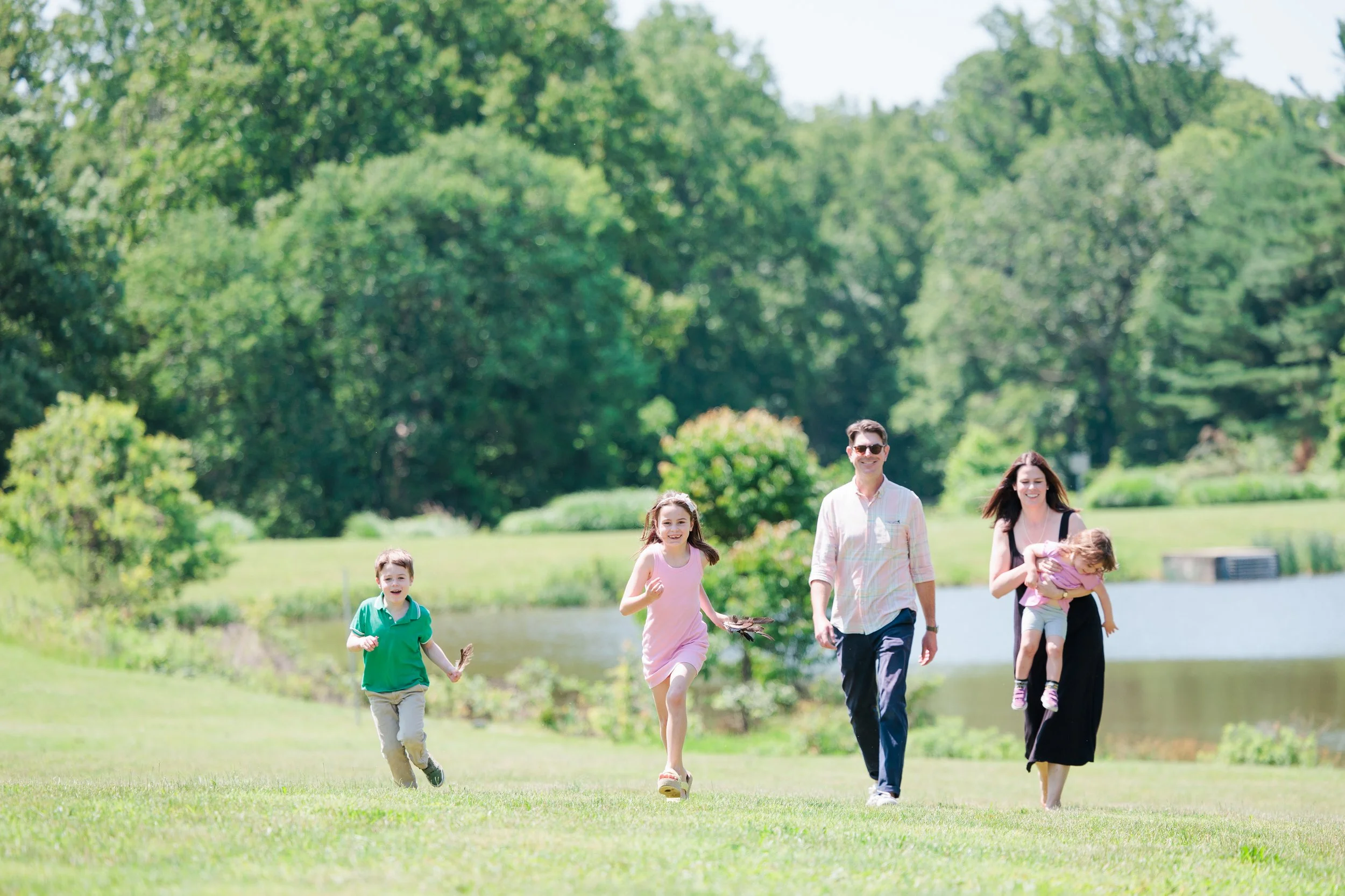 Family running together across an open field during a playful outdoor family photo session in Maryland