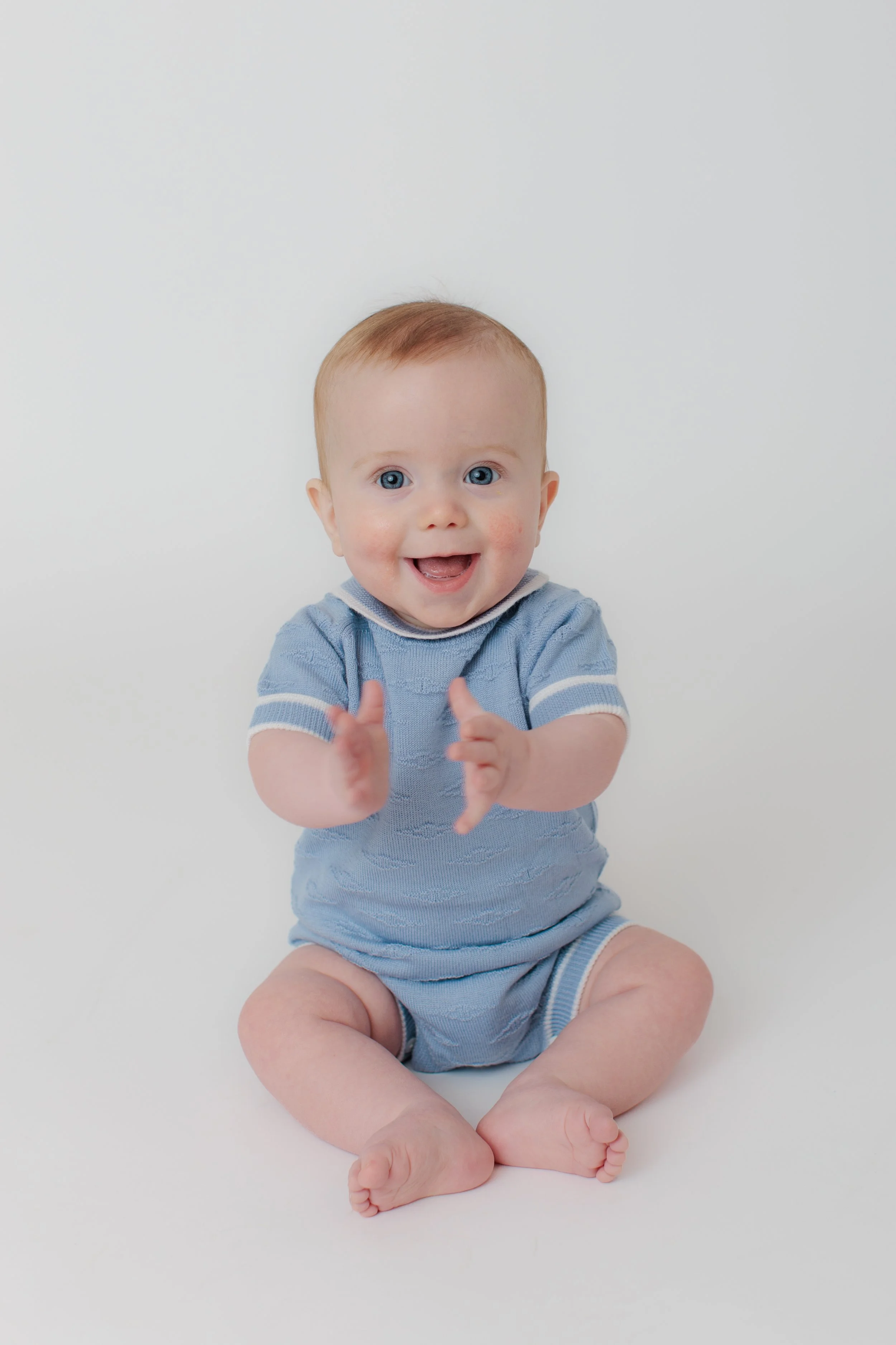 Baby boy blue eyes smiling at camera in Silver Spring studio