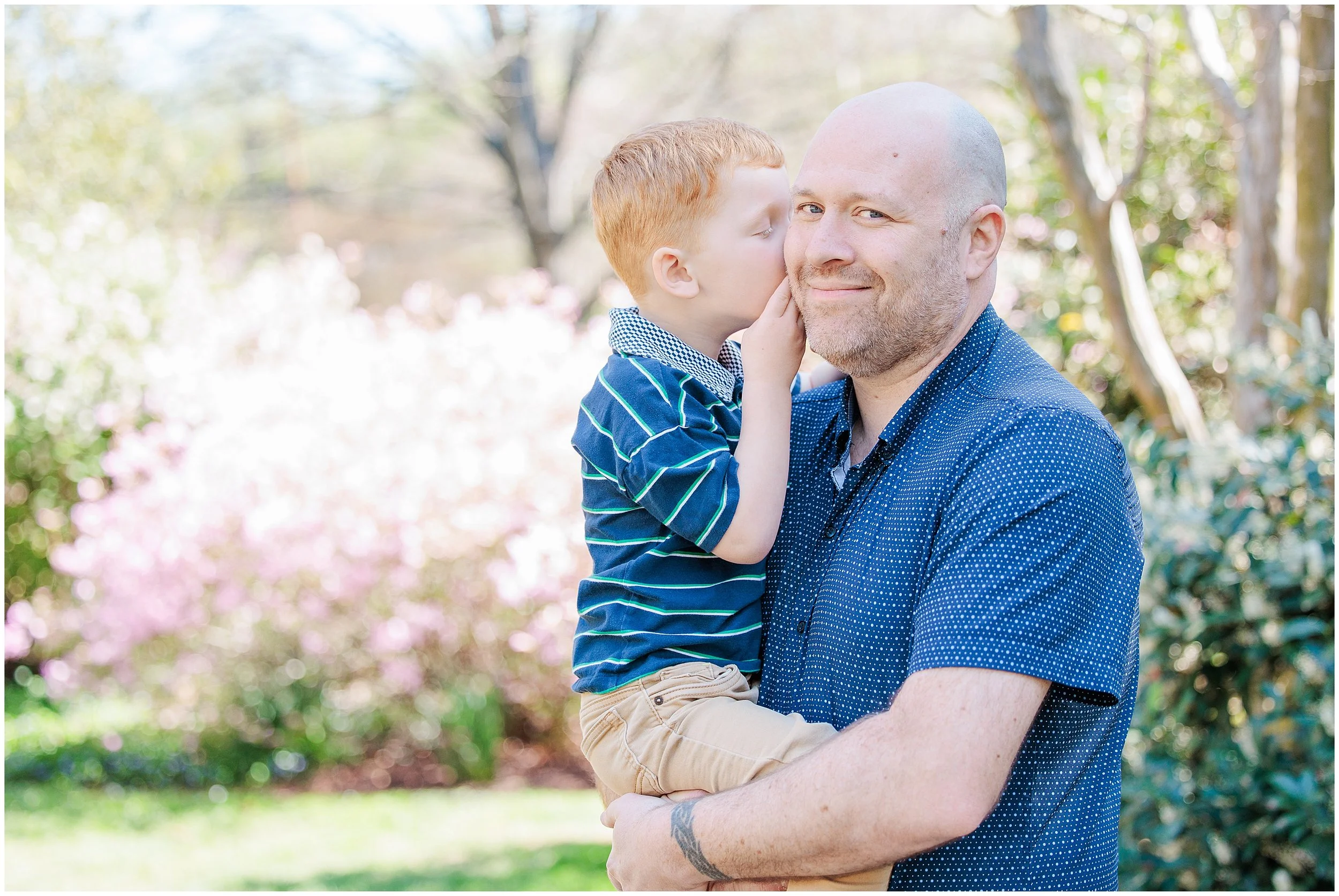 father holding young son close during candid spring family photo session in Maryland