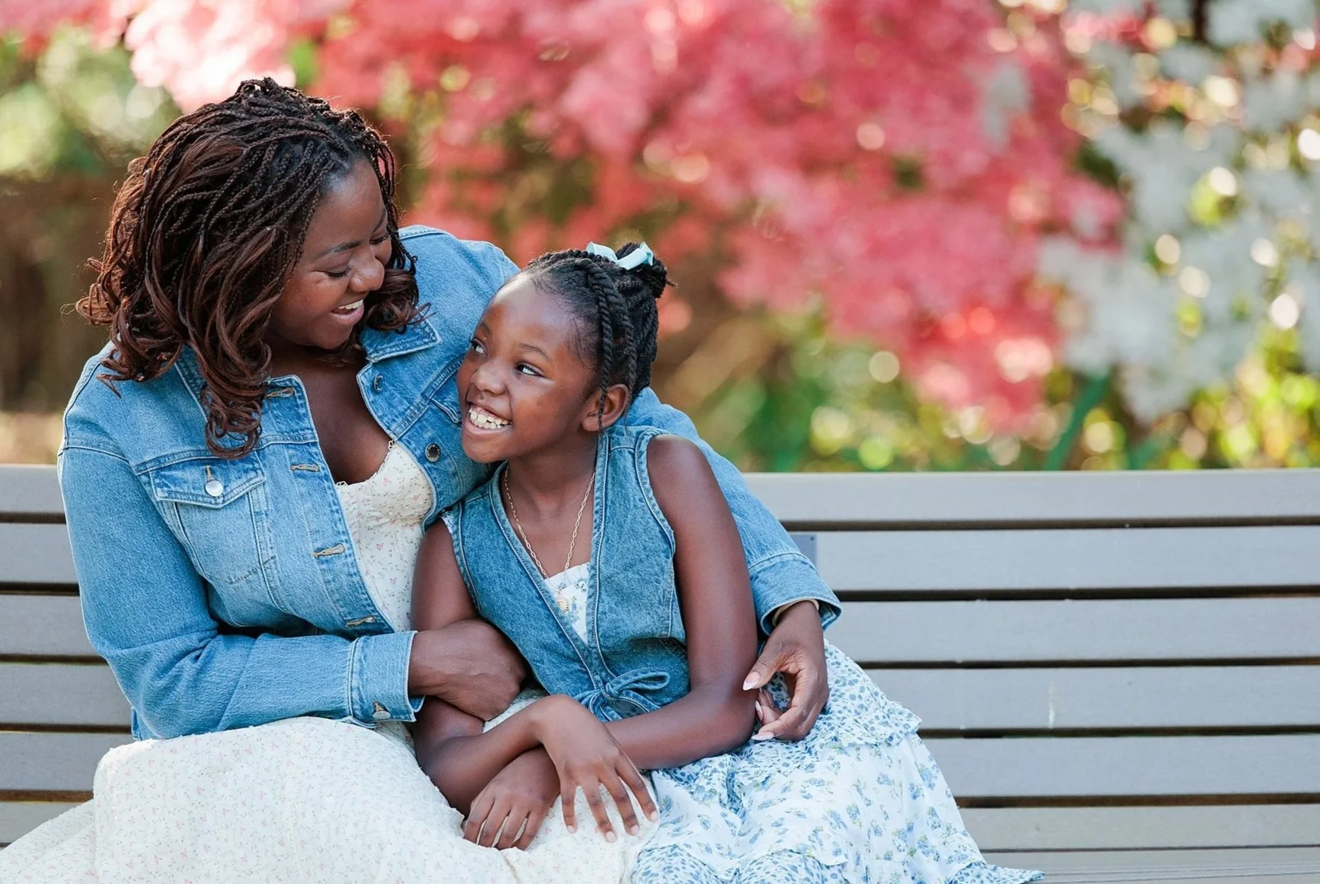 mother and daughter sitting on bench in front of red fall colored tree by family photographer in Maryland