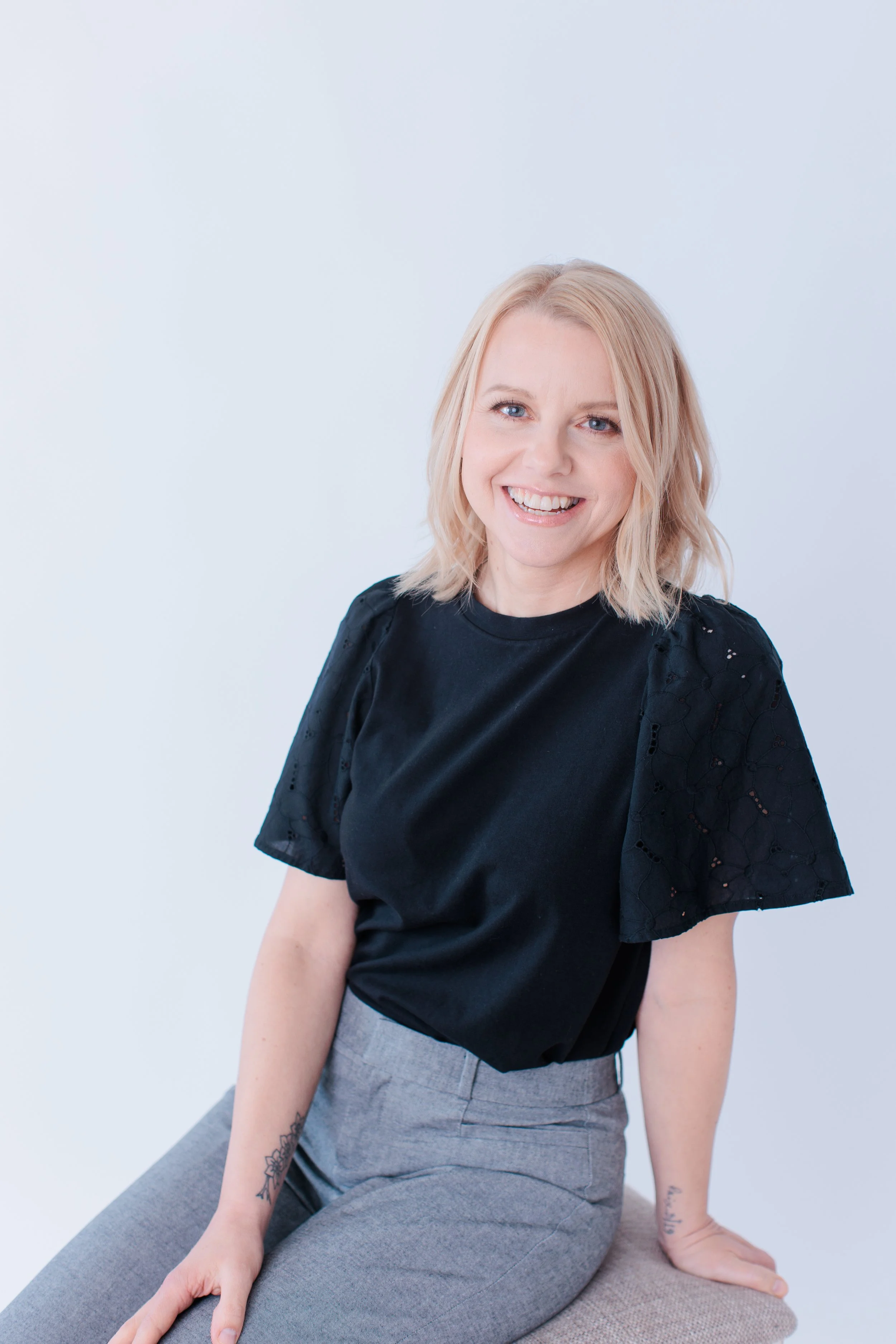 headshot of a blonde women in white studio on stool