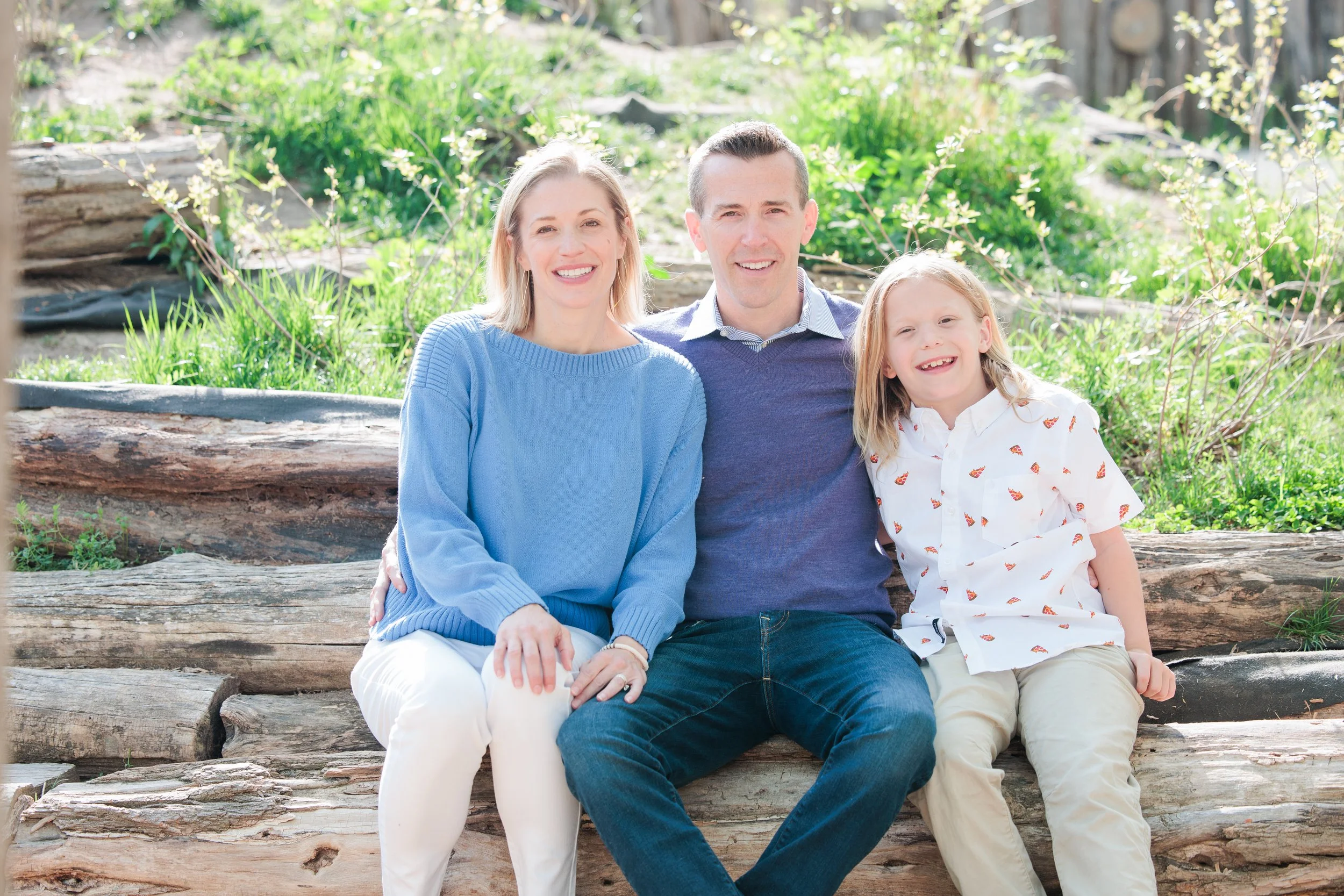 Family sitting together on logs during a relaxed outdoor family photo session in Maryland