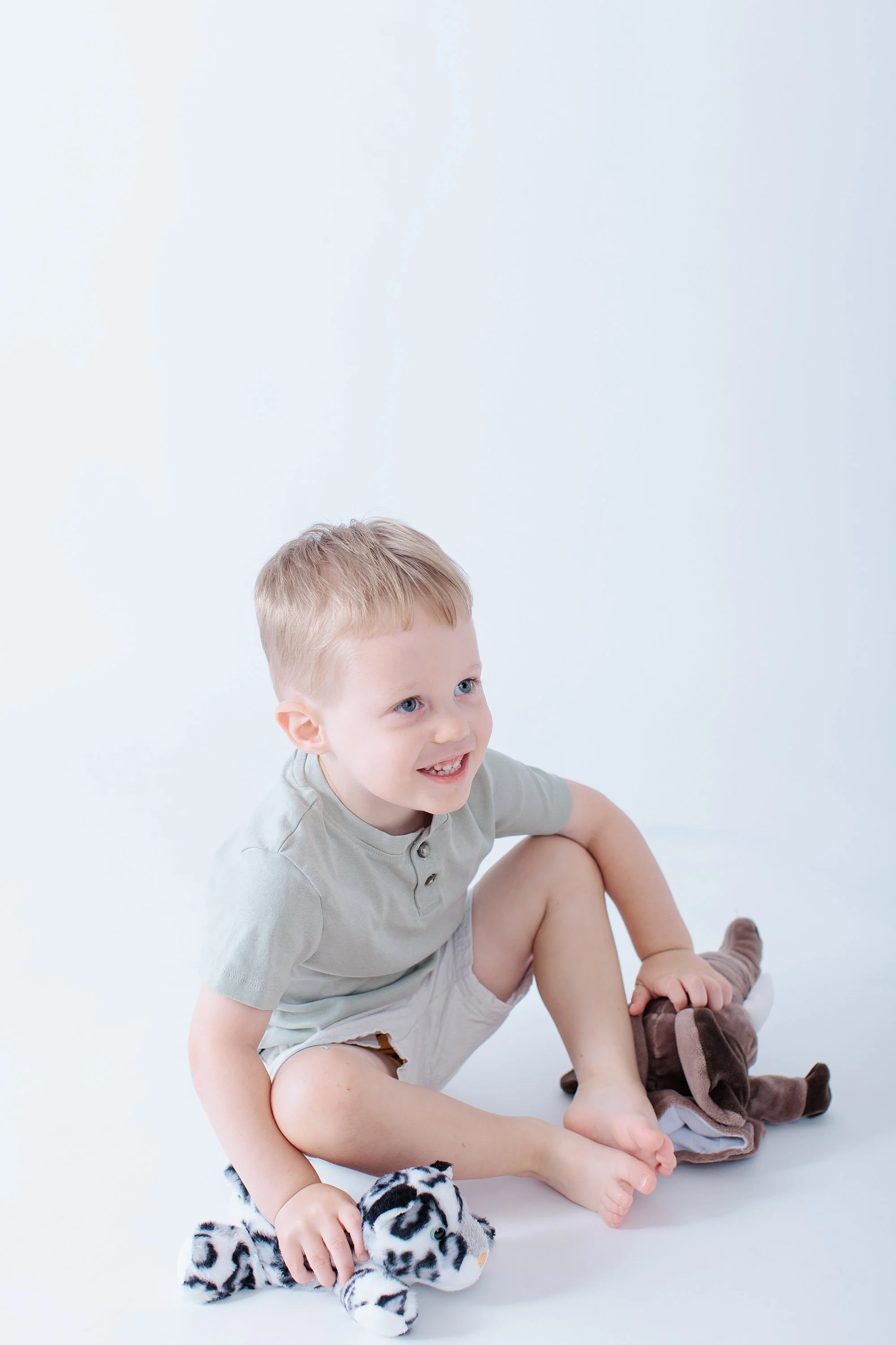 boy sitting on white studio floor for photo session