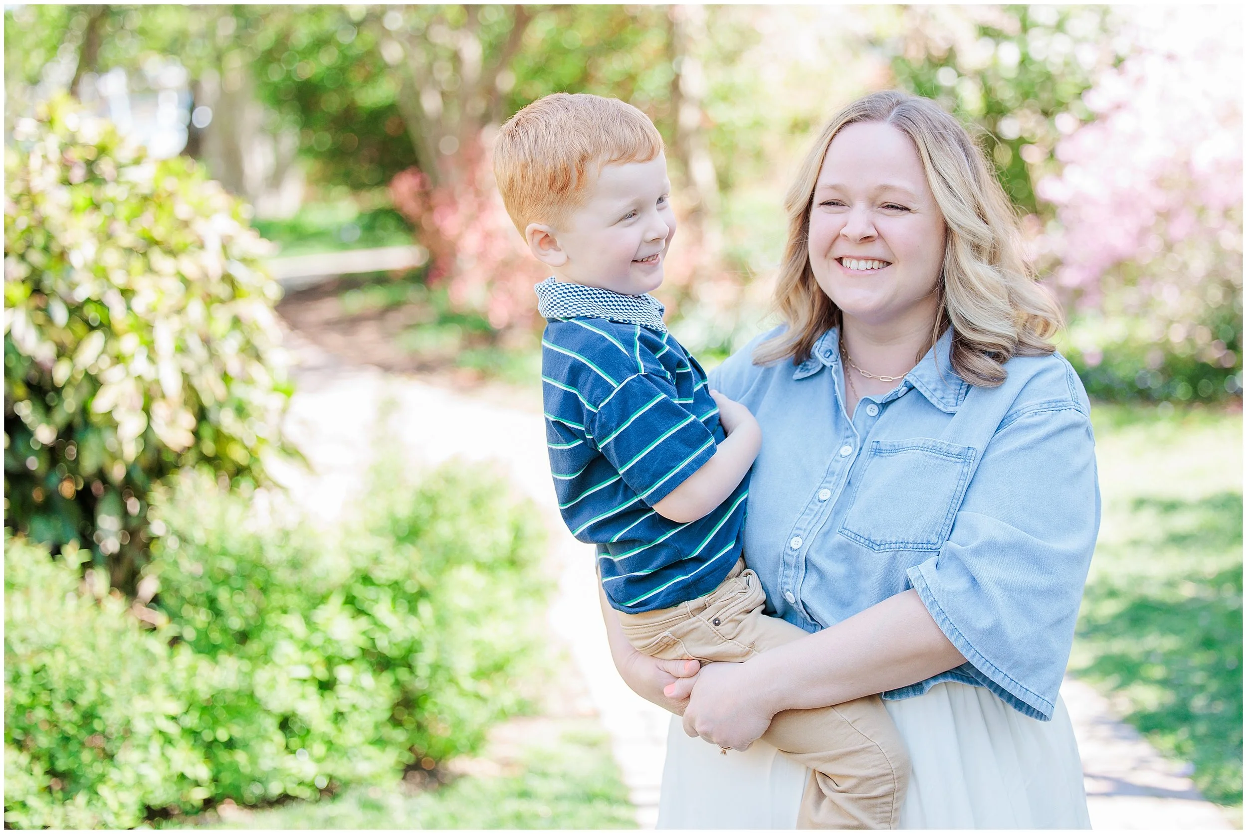 mother holding young son and smiling during outdoor spring family photos in Kensington MD
