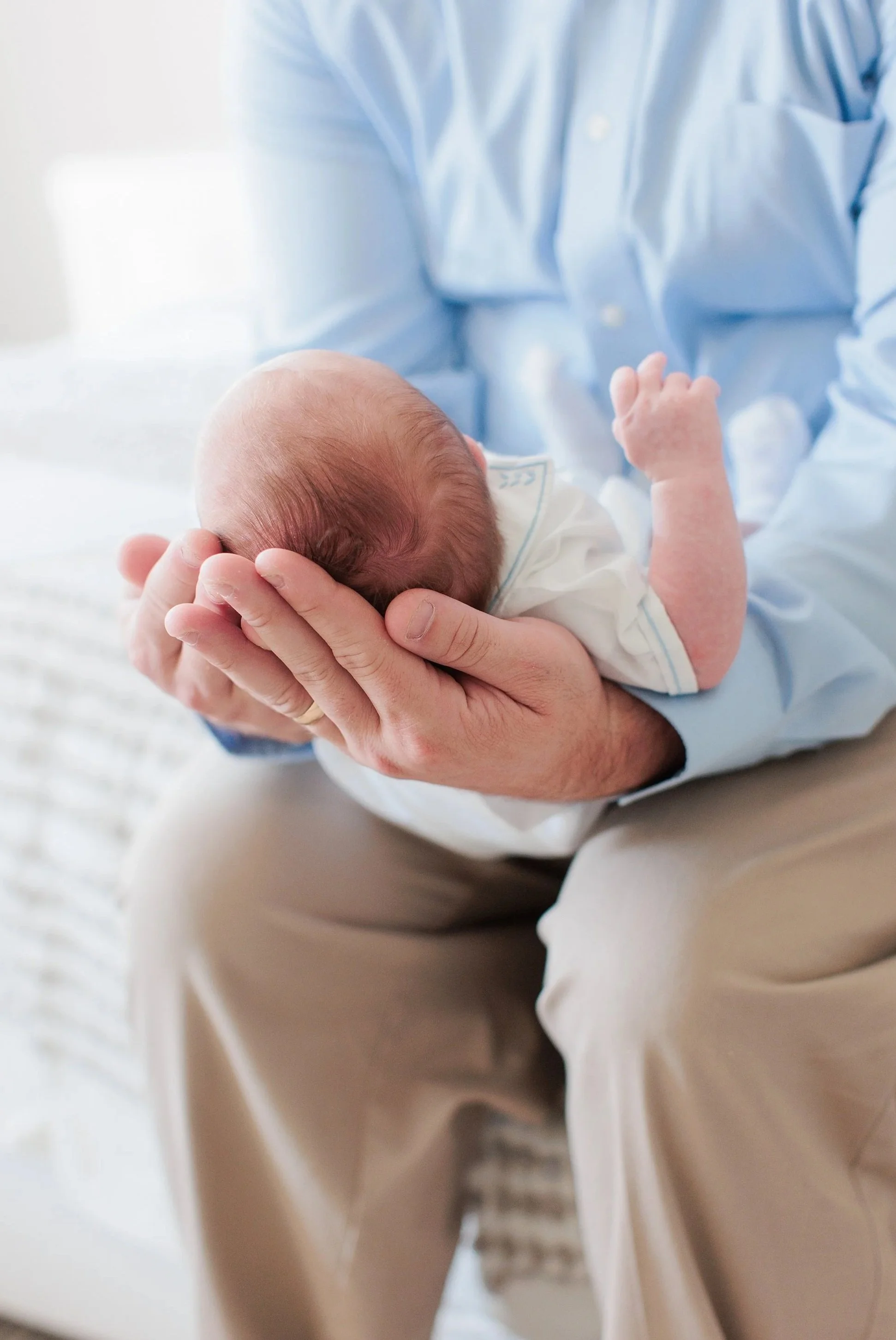 Dad holding newborn baby at home during newborn photo session