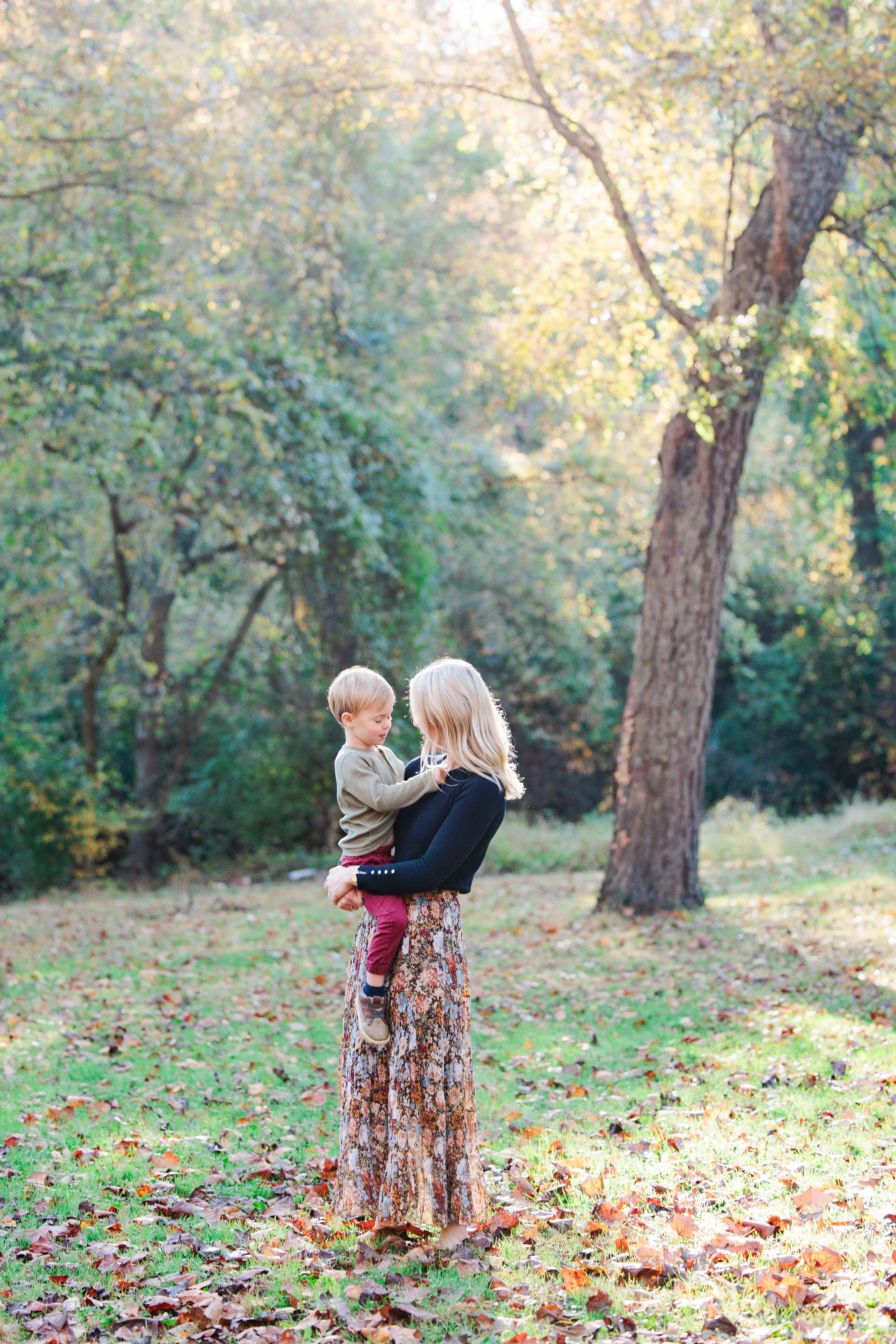 Mother holding toddler in a wooded field during a natural family photo session in Montgomery County, Maryland