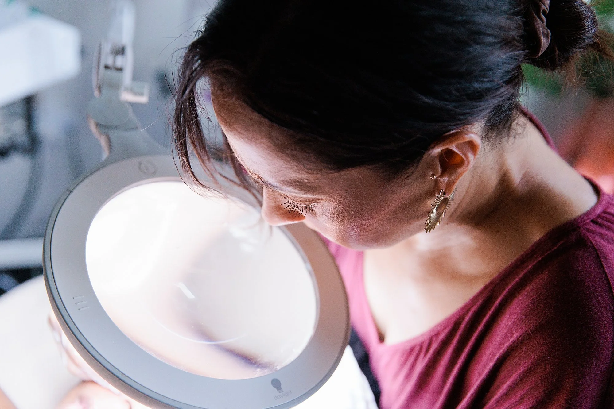 Esthetician looking through magnifying glass