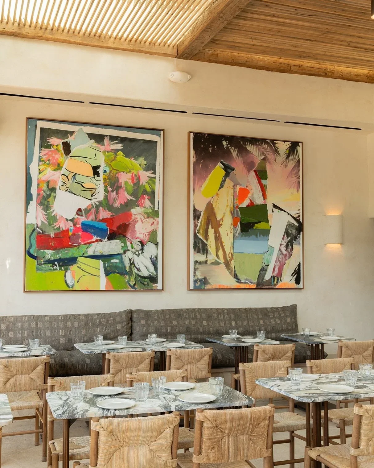 Design-driven dining. Sun-drenched interiors featuring custom contemporary art and marble tables at Great White Restaurant Brentwood, designed by founders Sam Trude and Sam Cooper.