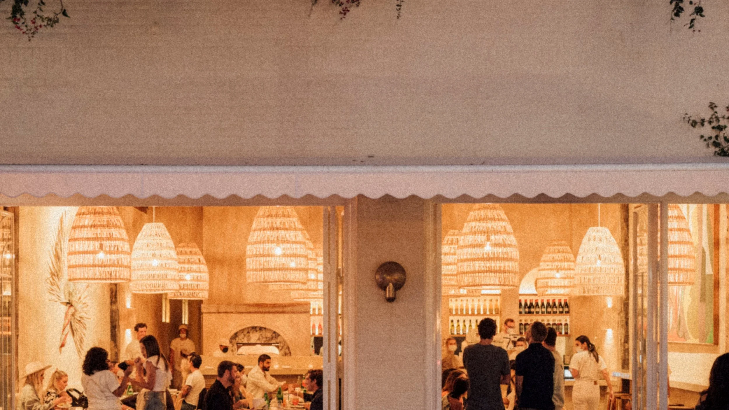 Warm woven basket lighting illuminates the open-air architecture at Great White Restaurant Venice, creating the perfect golden-hour atmosphere near the beach.