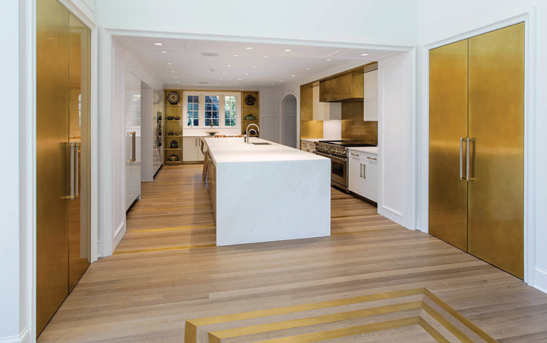 In overhauling this Pennsylvania kitchen, Amuneal added hand-polished gloss-white lacquer cabinets complemented by several brass elements, including cabinetry, shelving, retractable brass doors and floor inlays. Photo by Goldenberg Photography