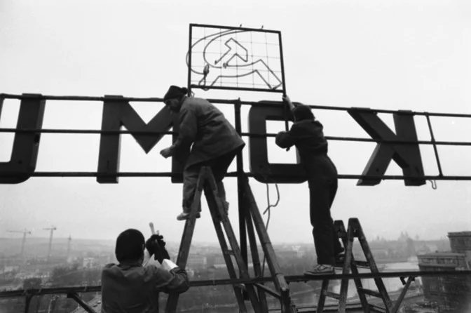 Workers remove a hammer and sickle from a neon sign that reads “Glory to Communism,” visible on the roof of the Communist-run electricity-board headquarters in Czechoslovakia in 1989. (AP)