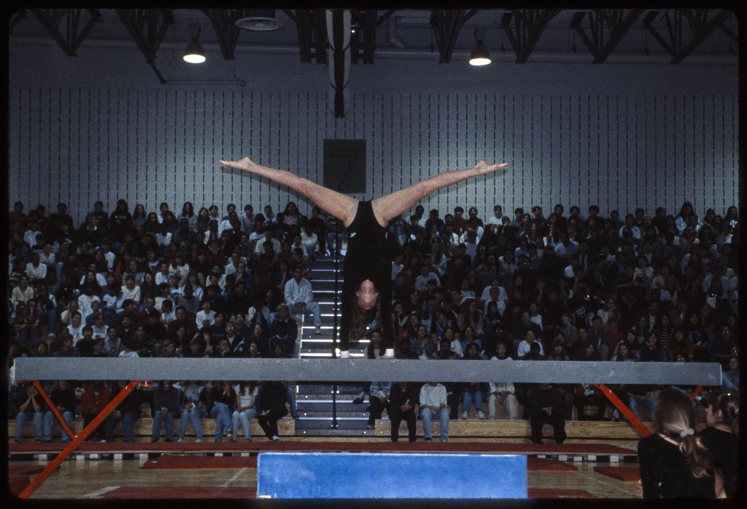 Female trouper straddle handstand on beam at road show