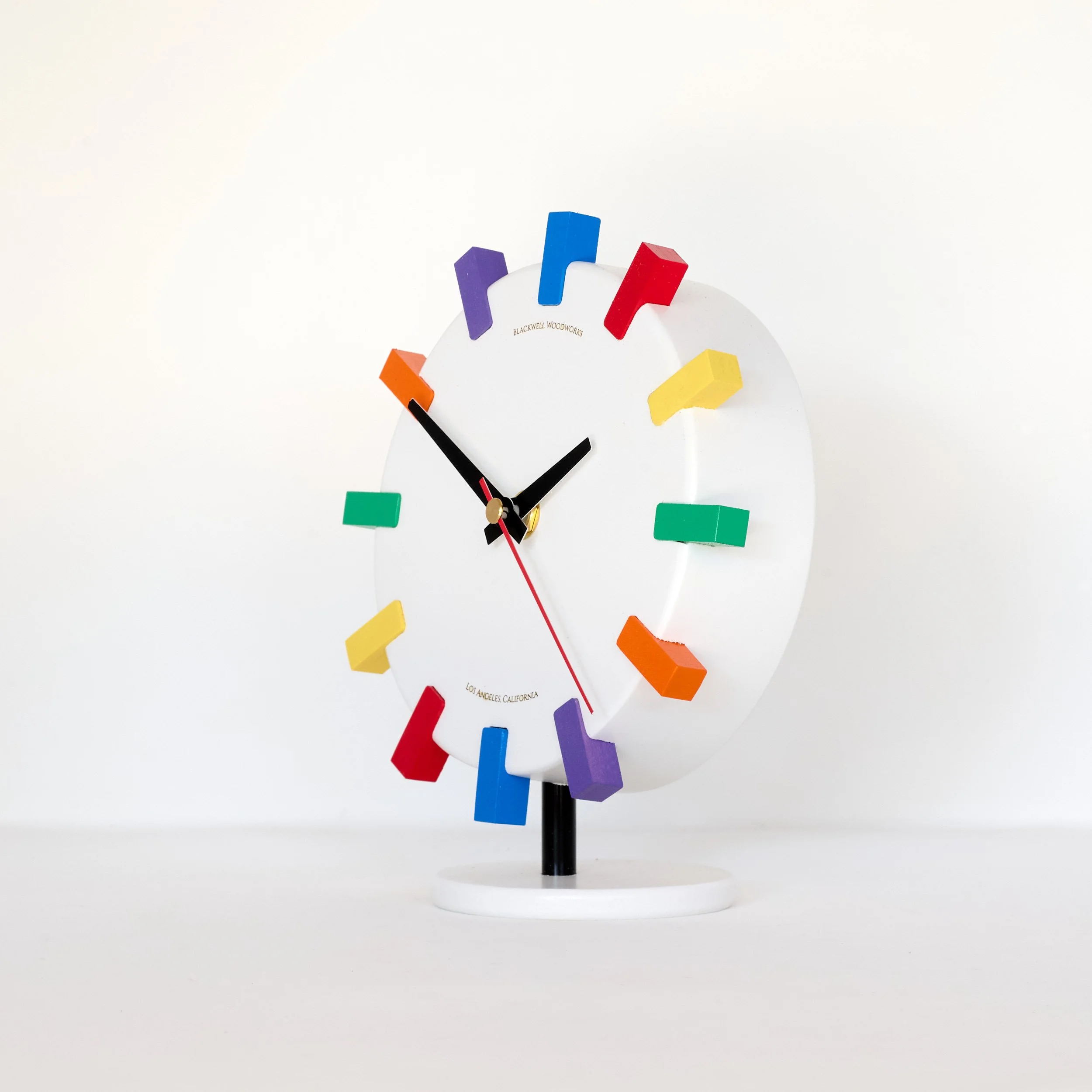 White sculptural wood clock with vibrant color accents