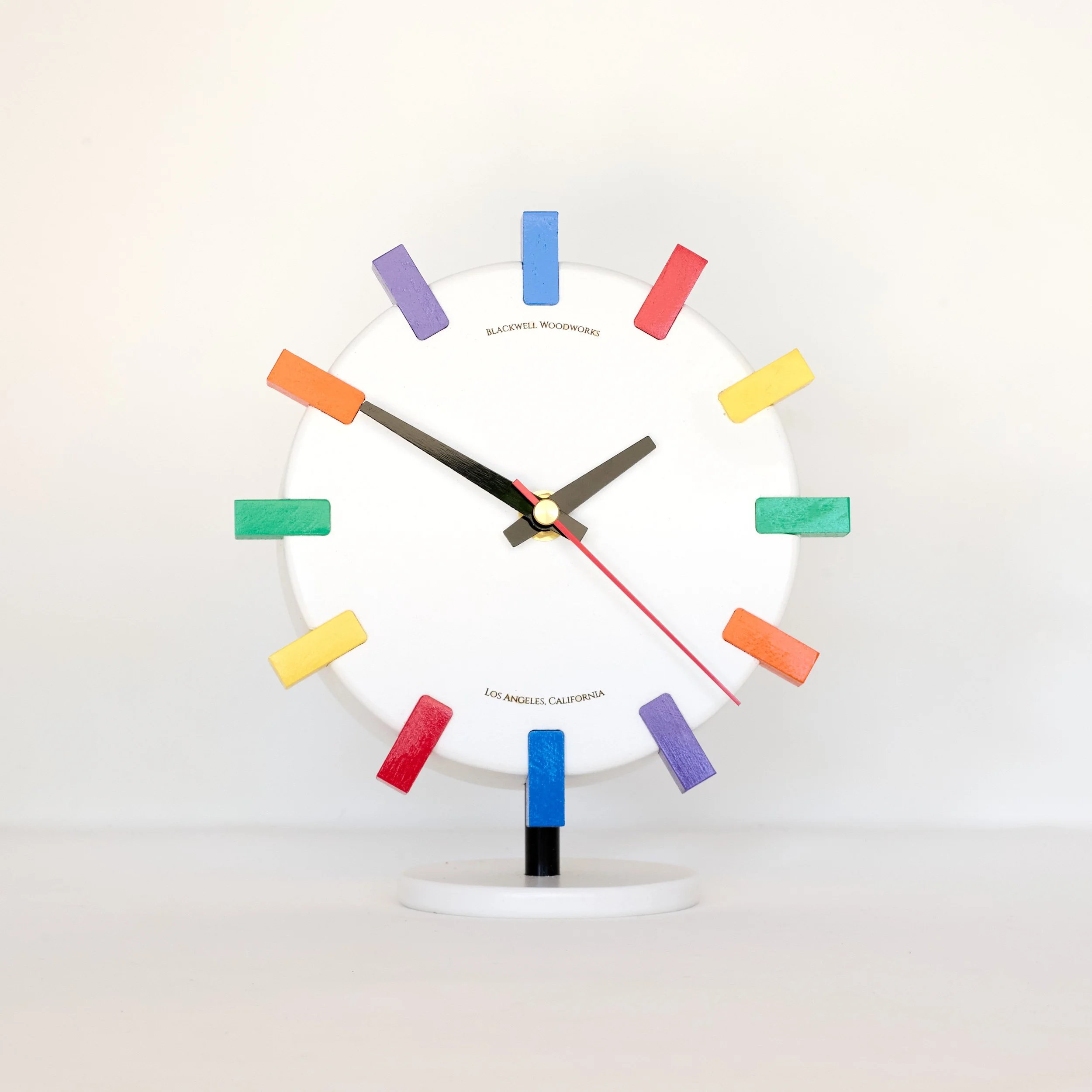 White sculptural wood clock with vibrant color accents