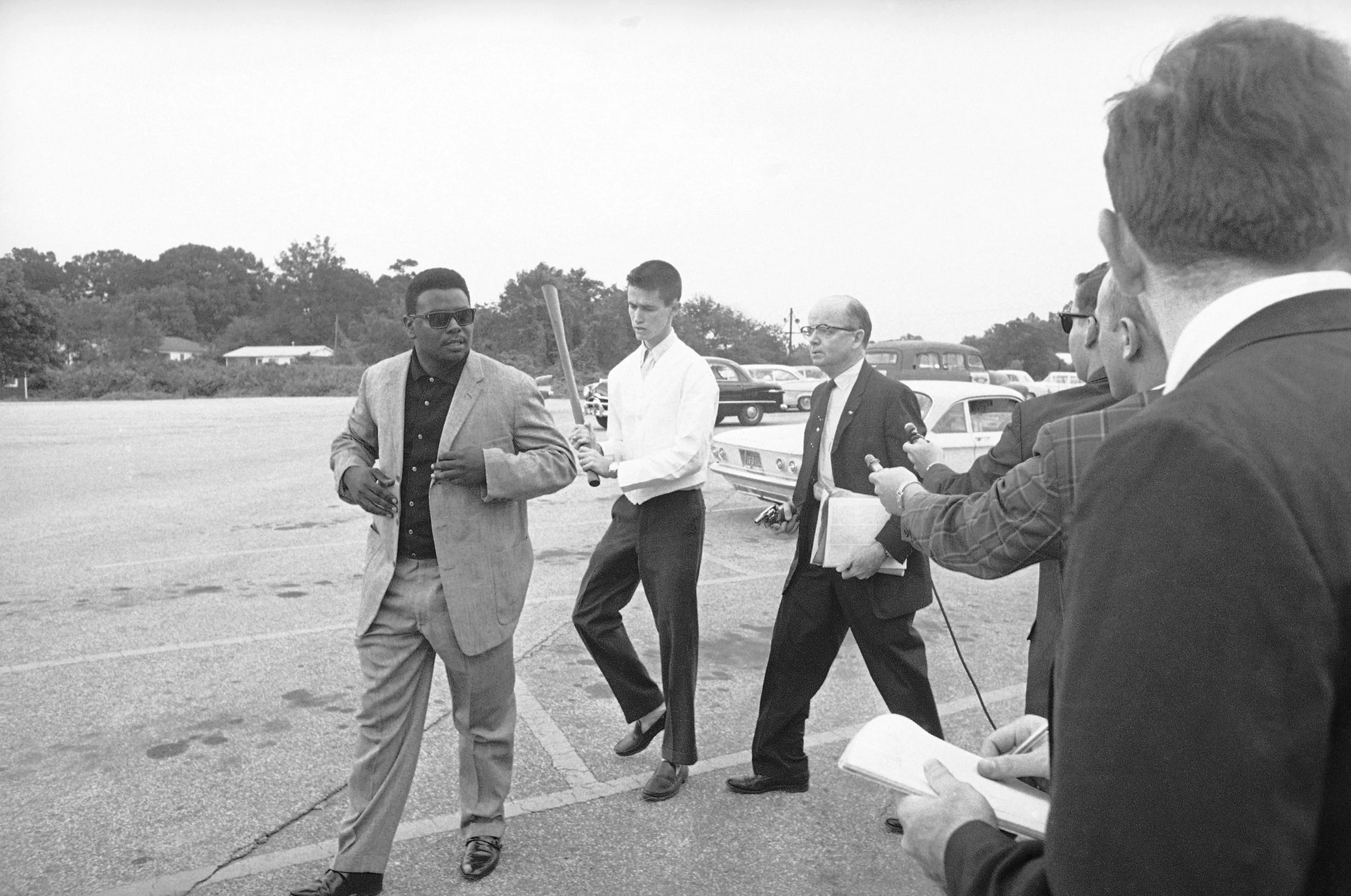 PAGE 86: THE DAY FOLLOWING THE SIGNING OF THE CIVIL RIGHTS ACT OF 1964 BY PRESIDENT LYNDON B. JOHNSON, REVS. GEORGE WILLIS JR., WOODROW T. LEWIS, AND ALBERT L. DUNN ATTEMPTED TO INTEGRATE THE PICKRICK RESTAURANT OWNED BY STAUNCH SEGREGATIONIST LESTER MADDOX. THE THREE MEN WERE DENIED SERVICE AND SHOVED OUT OF THE RESTAURANT. AN ASSOCIATED PRESS PHOTOGRAPHER CAPTURED REV. WILLIS JR. (LEFT) WALKING TO HIS CAR FOLLOWED BY MADDOX, POINTING A SHORT PISTOL, AND HIS SON HOLDING AN AX HANDLE (PERMISSION OF THE ASSOCIATED PRESS). 