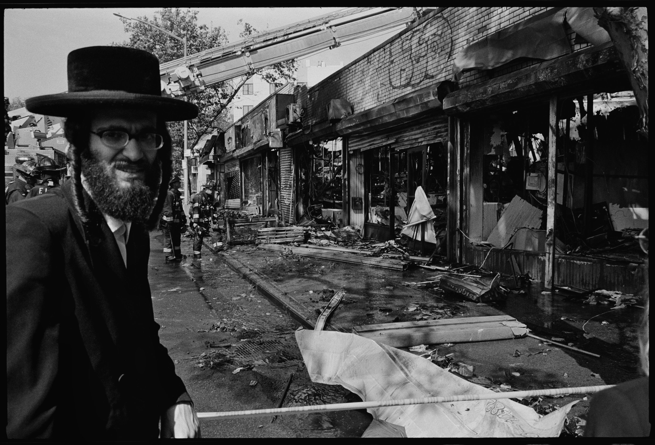 Man in front of burned storefronts, Williamsburg St E