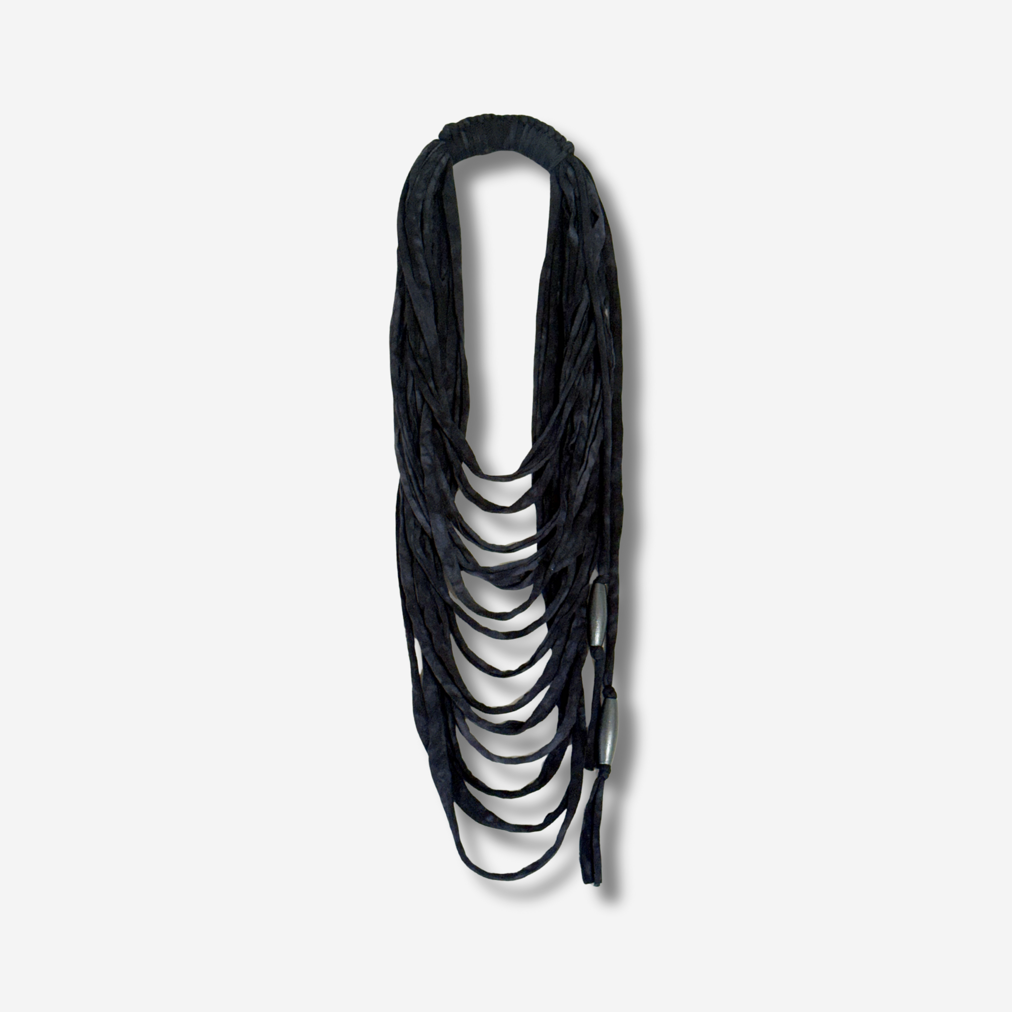 Black fabric multi-strand necklace hanging against a plain light background.
