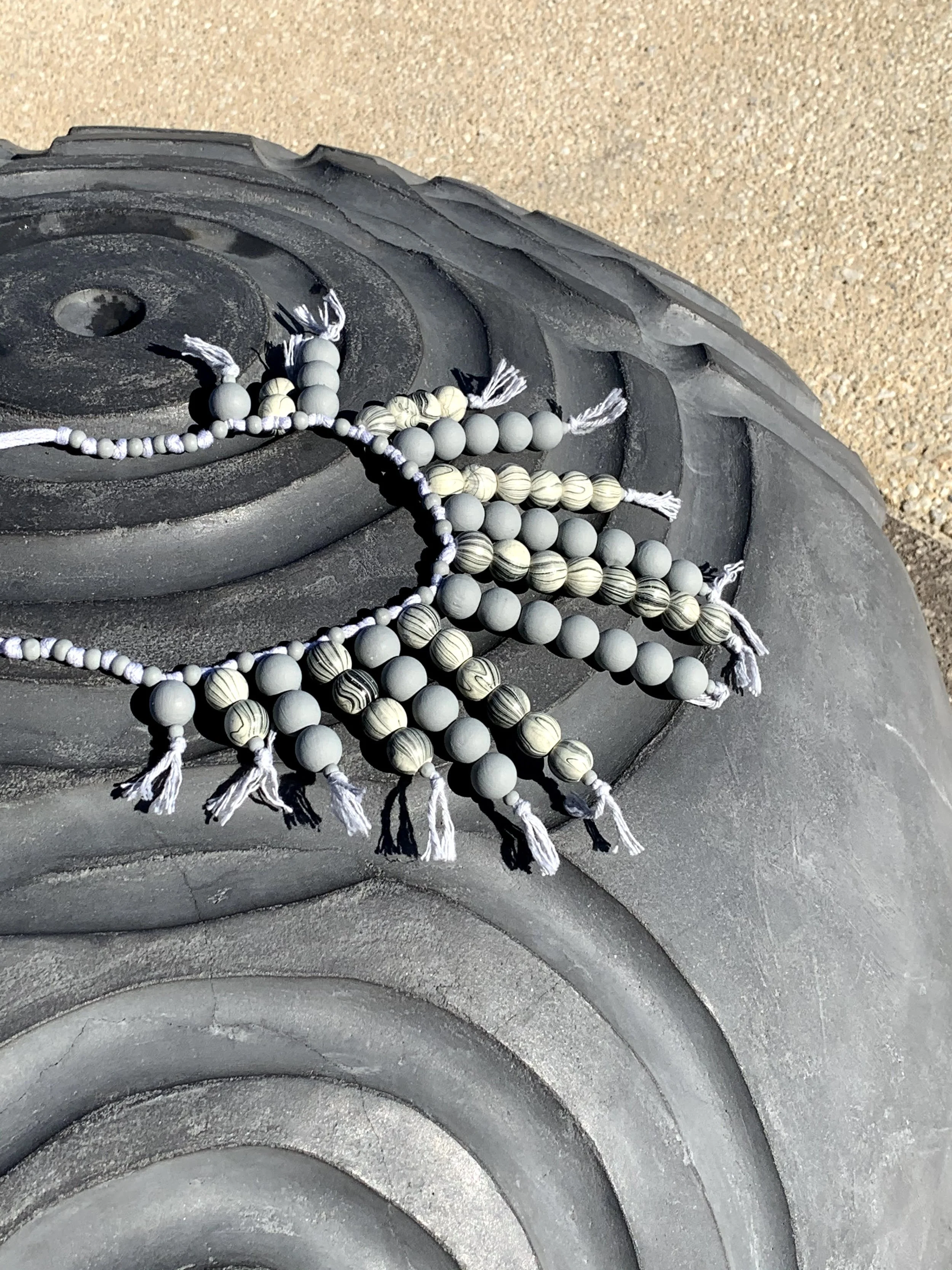 Gray beaded necklace resting on a sculpture.