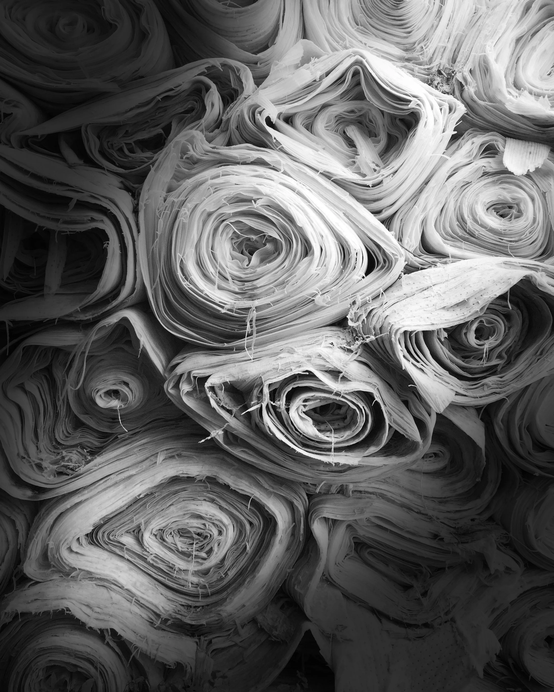A close-up image of tightly rolled fabric in black and white.