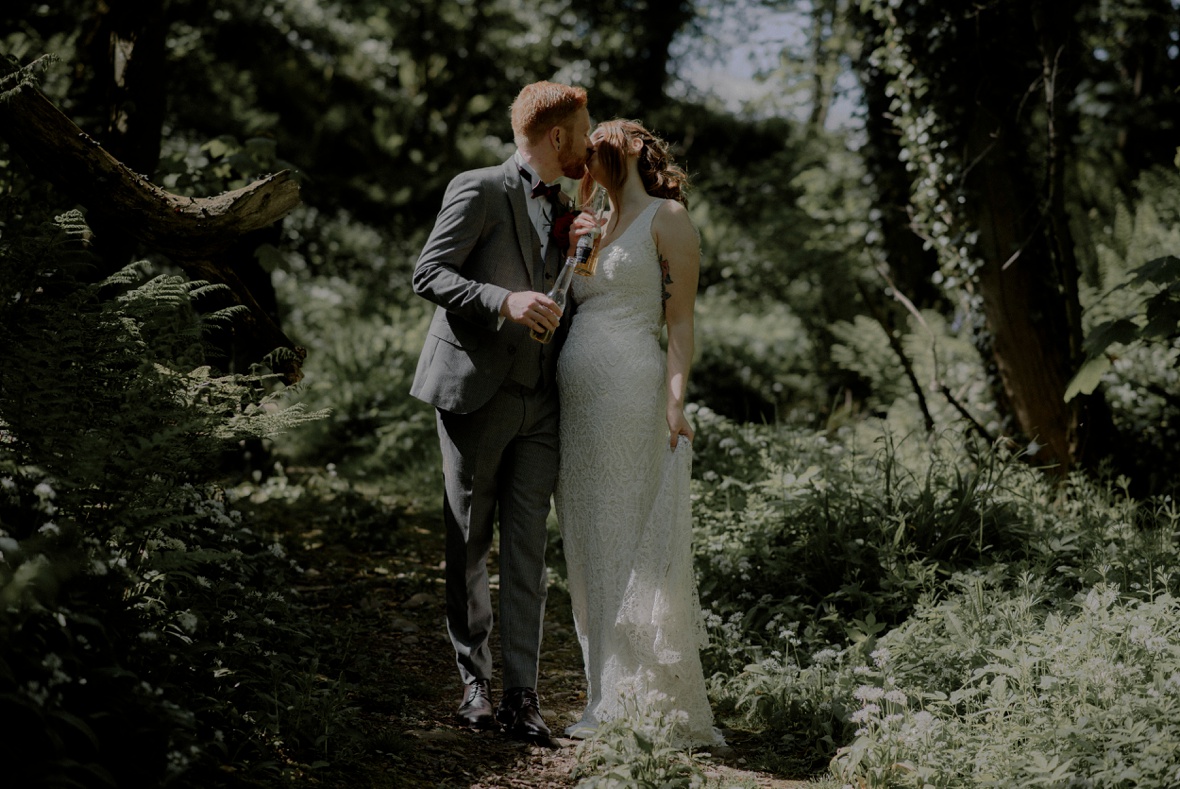 couple is kissing whilst holding bottle of beer