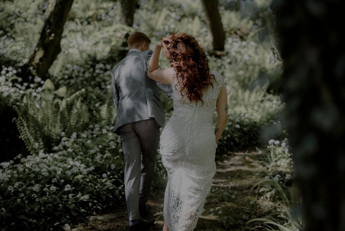 bride and groom are walking in forest