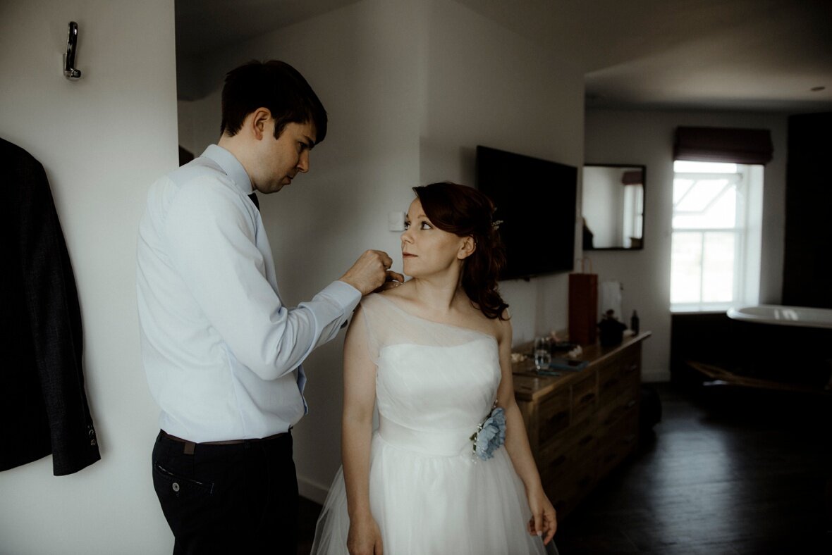 groom is helping bride to get ready