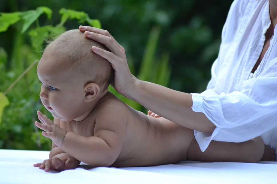 Osteopata con bebe, mano sobre la cabeza.