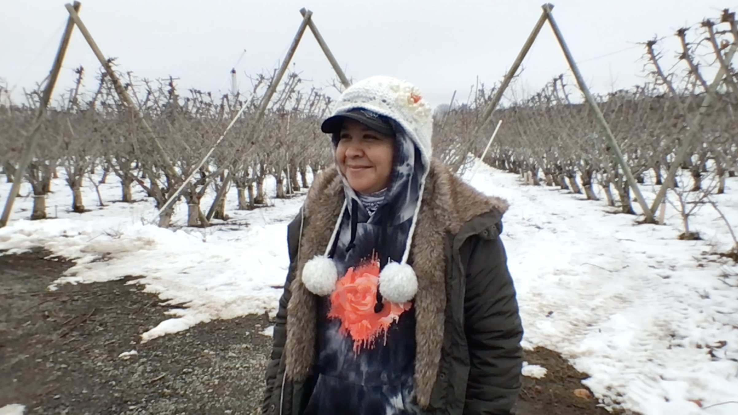 Aurora Vega from NWFM, standing in an apple orchard during winter for an interview with Ganaz.