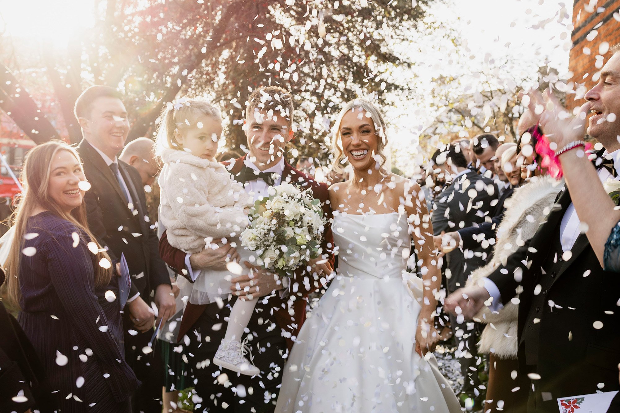 smiling-wedding-couple-with-daughter-in-confetti.jpg