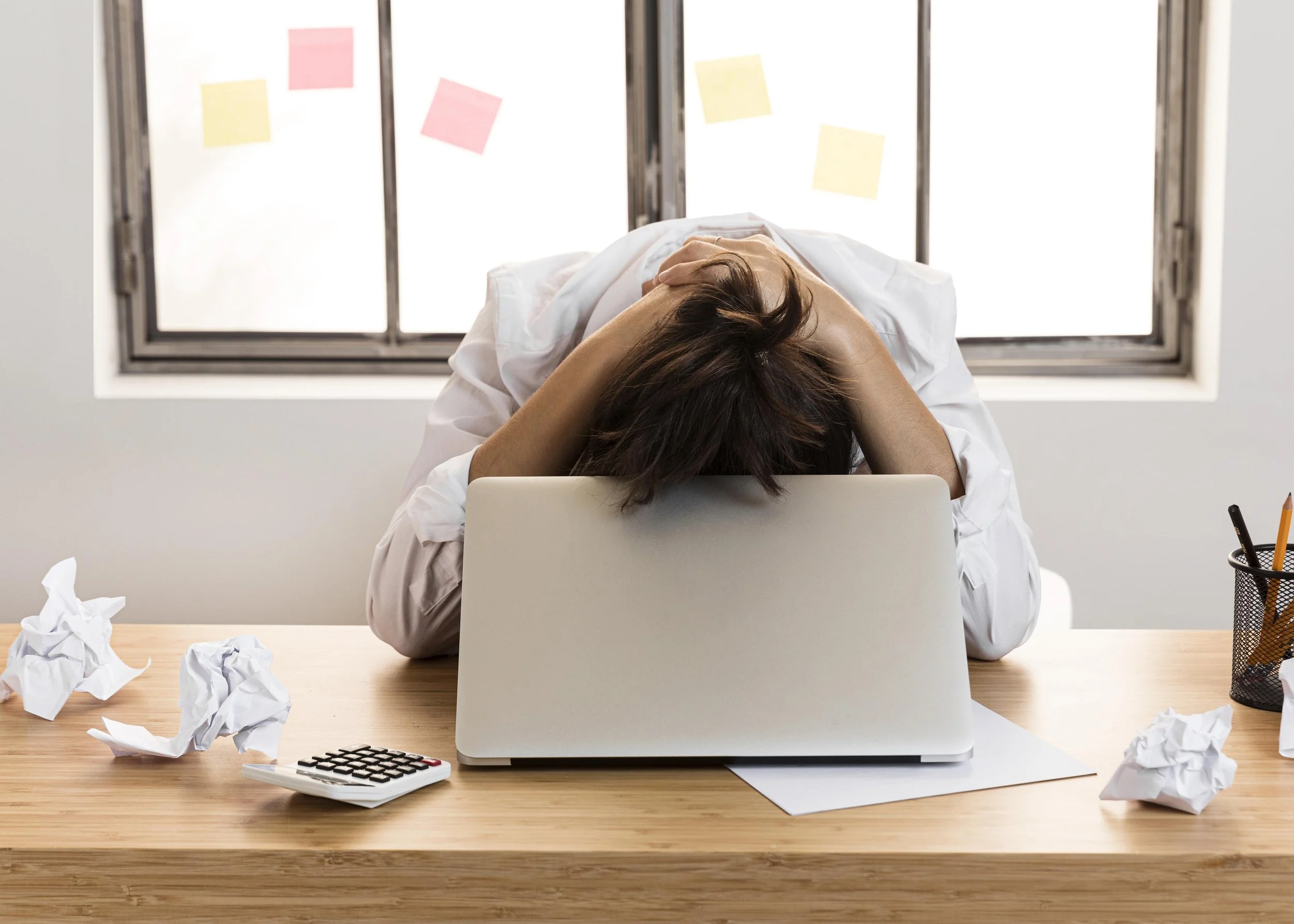 An employee resting their head on their laptop