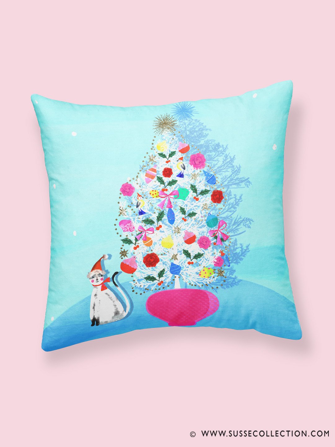 A photograph of a colourful illustration of a cat and mid century Christmas Tree.as a pillow case