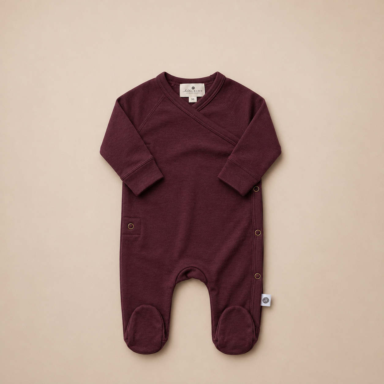Vinröd babyoverall på beige bakgrund.png
