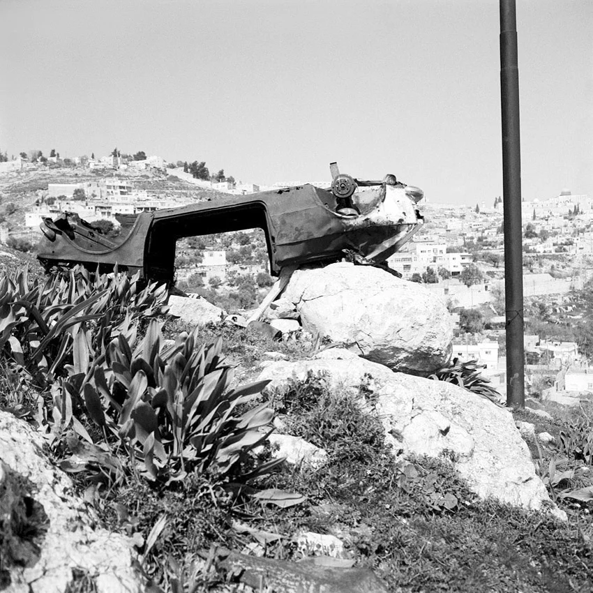 Carcasse de voiture sous les remparts de la vieille ville de Jerusalem. Le poteau fait partie de l’erouv de Jerusalem, délimitation symbolique de la communauté juive.