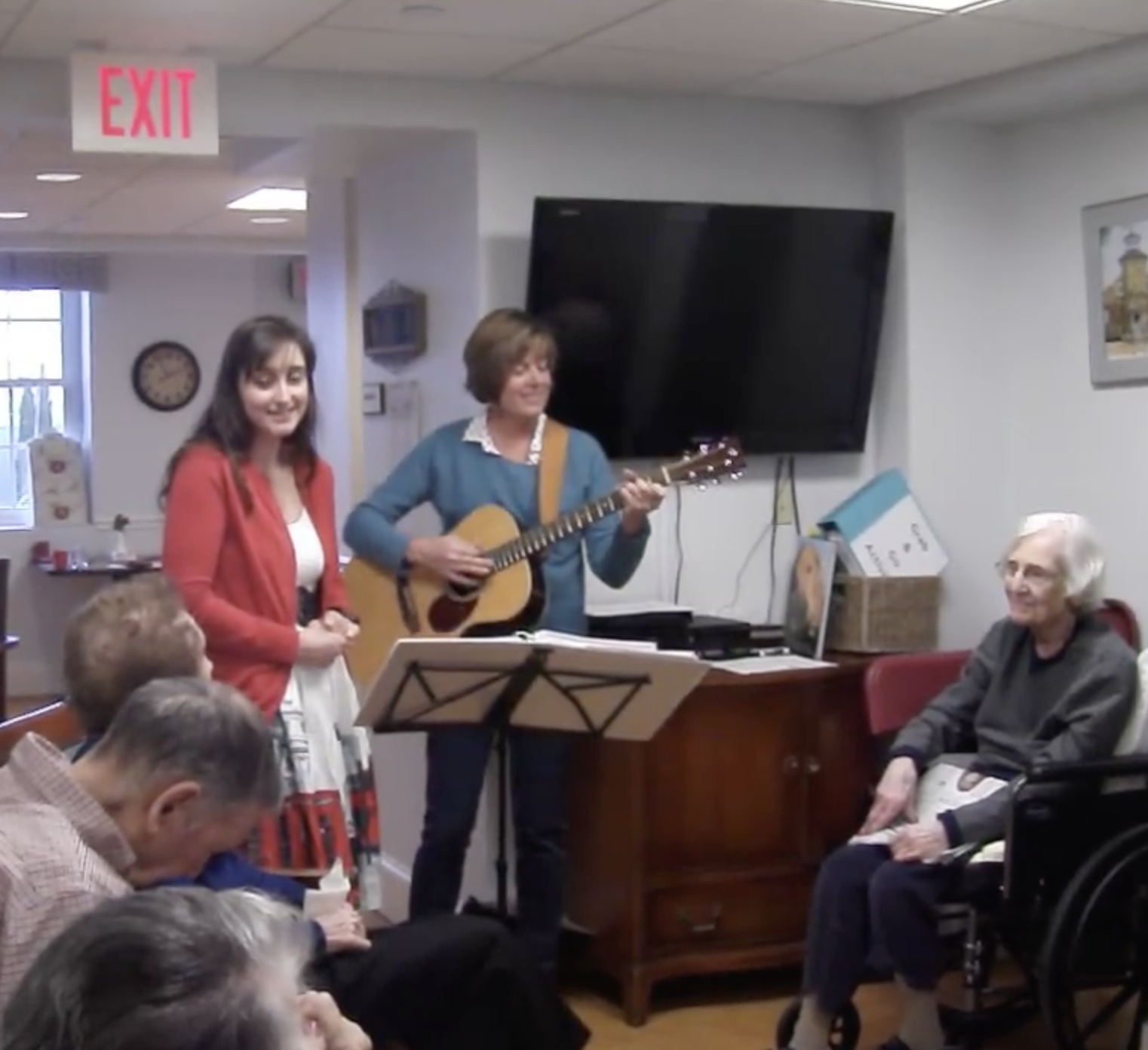 Benchmark Connections Coordinator Alyson Fowler , accompanied by Dot, sings “What a Wonderful World” to residents of Academy Point.