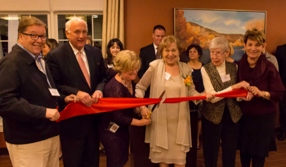 The Branches Executive Director Kelly Arnao shares the scissors while State Senator Richard Ross, far left, and State Representative Betty Poirier, far right, hold the ribbon with Benchmark CEO Tom Grape and the first two residents of The Branches, Elma Underhill and Harriet Weintraub.